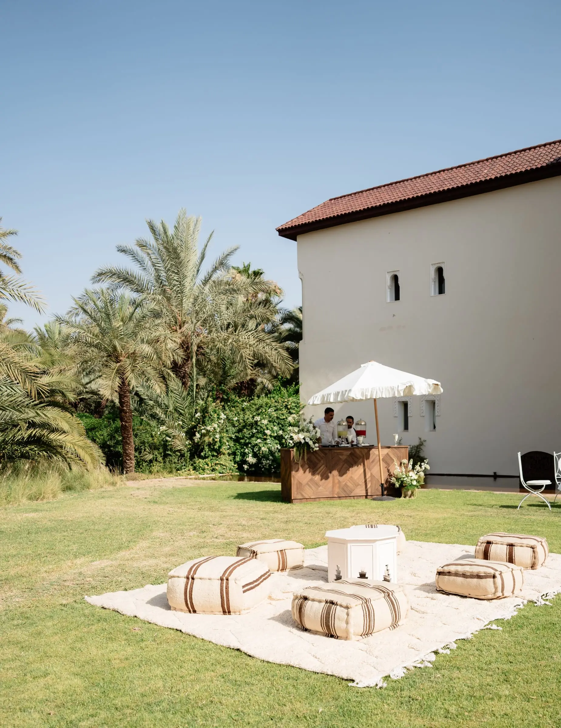 Lounge area with poufs and a white parasol on the garden lawn