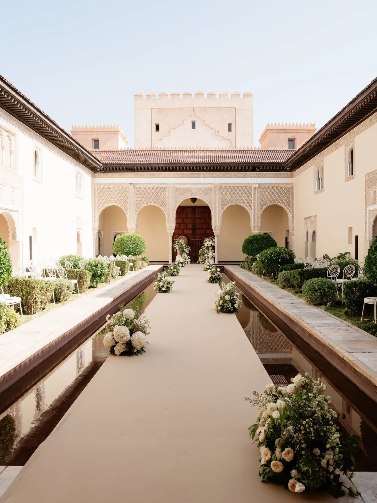 Ceremony aisle lined with flowers along the water basin of the Moorish courtyard