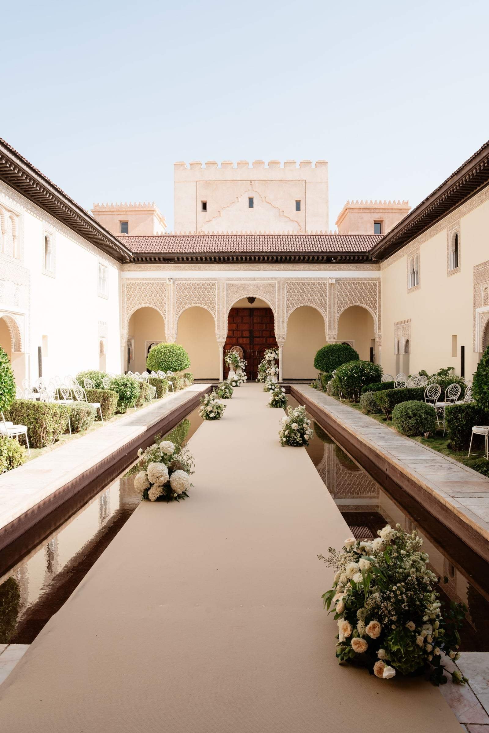 Ceremony aisle lined with flowers along the water basin of the Moorish courtyard