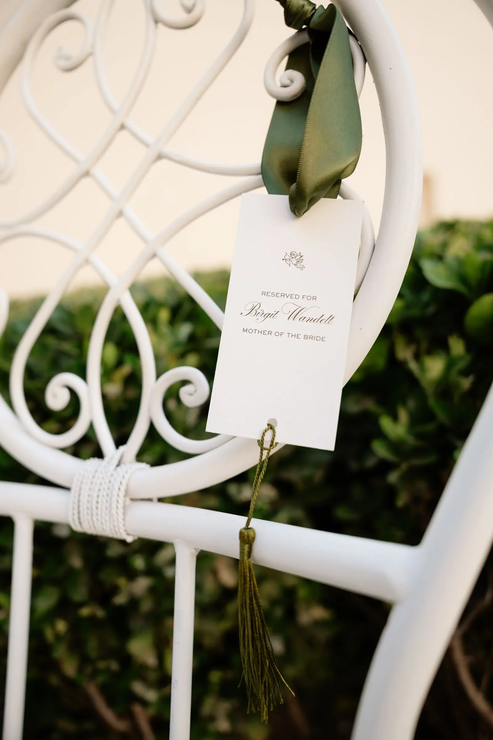 Name card tied with a green ribbon to a white ceremony chair