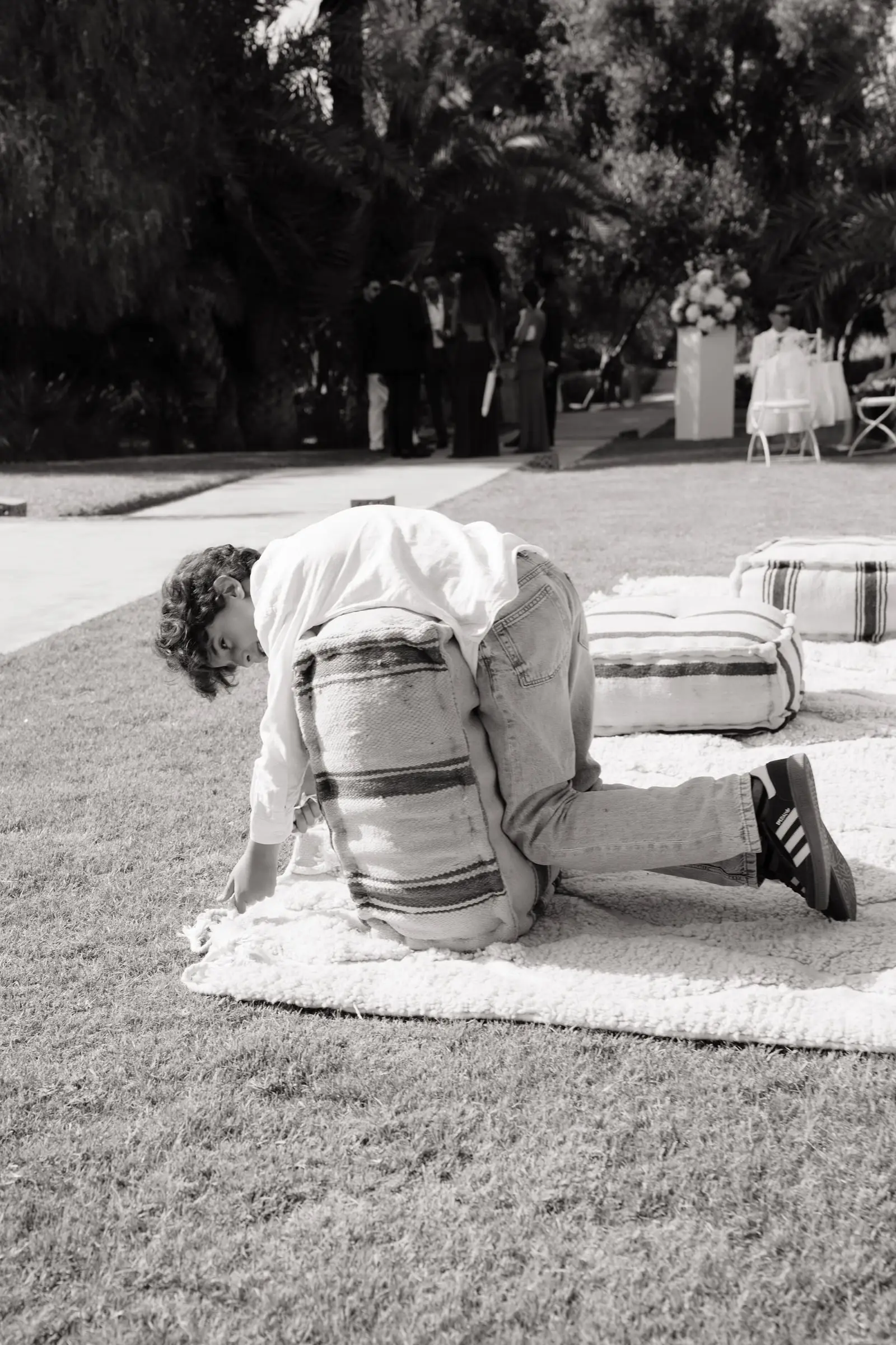 Black and white photo of a guest arranging poufs on the lawn