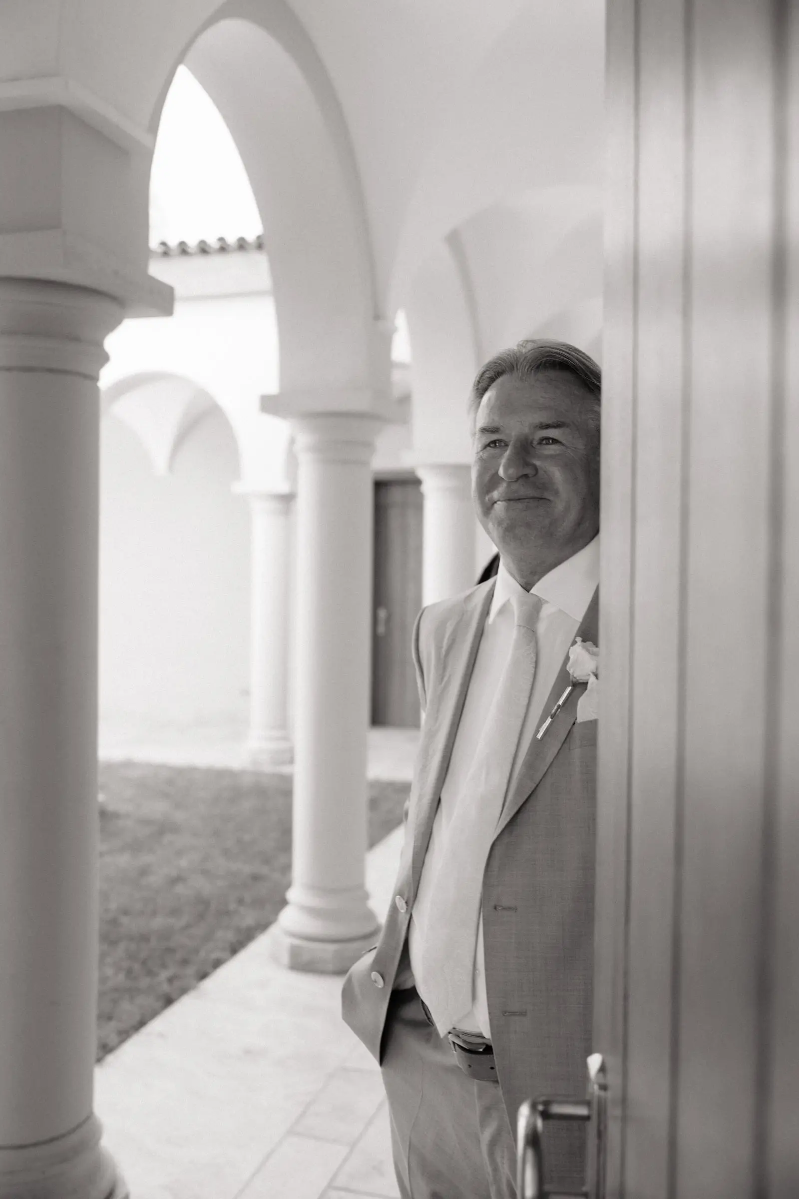 Black and white photo of the father of the bride waiting under the arcades