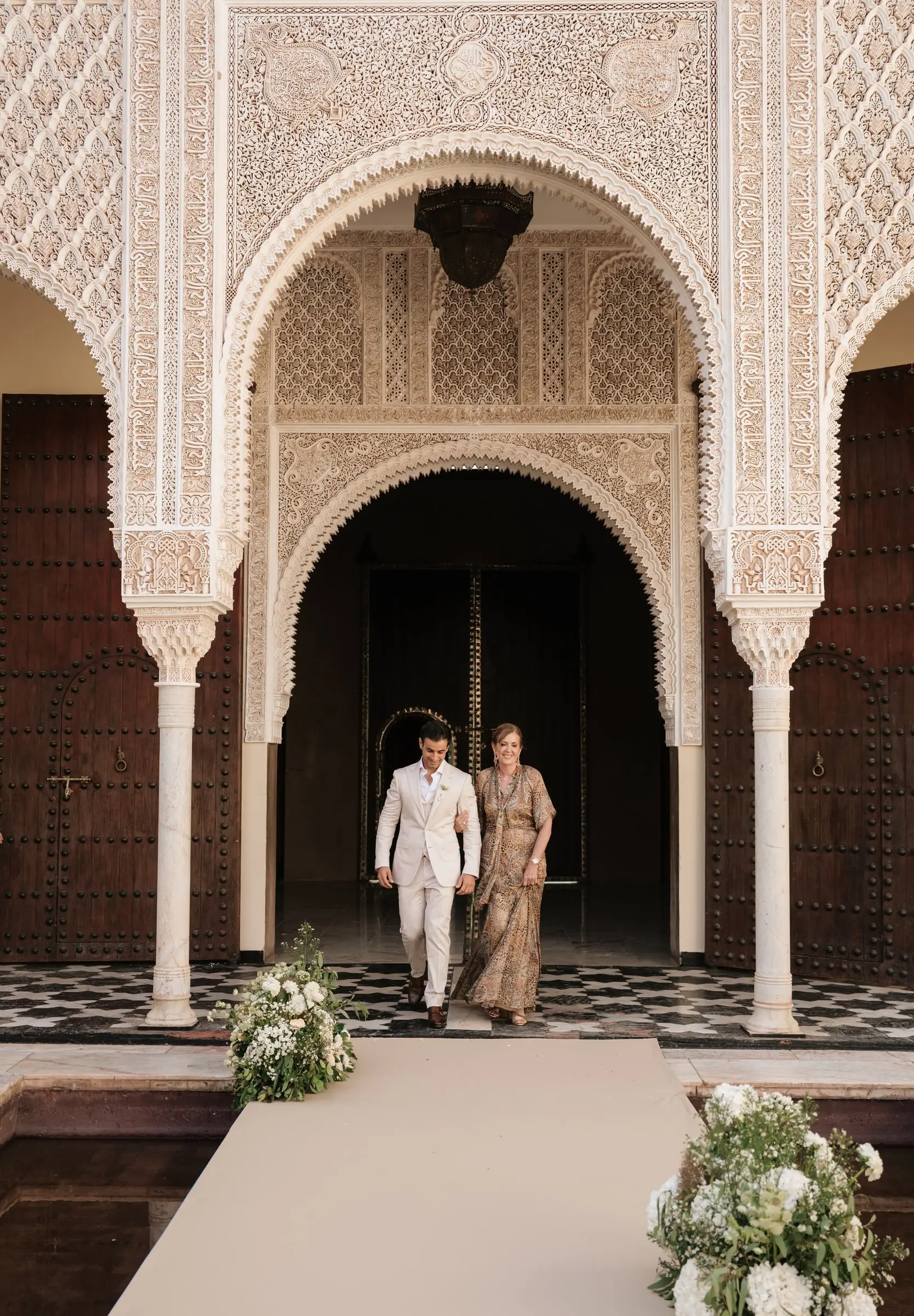 Groom walks down the aisle with his mother through the Moorish arch