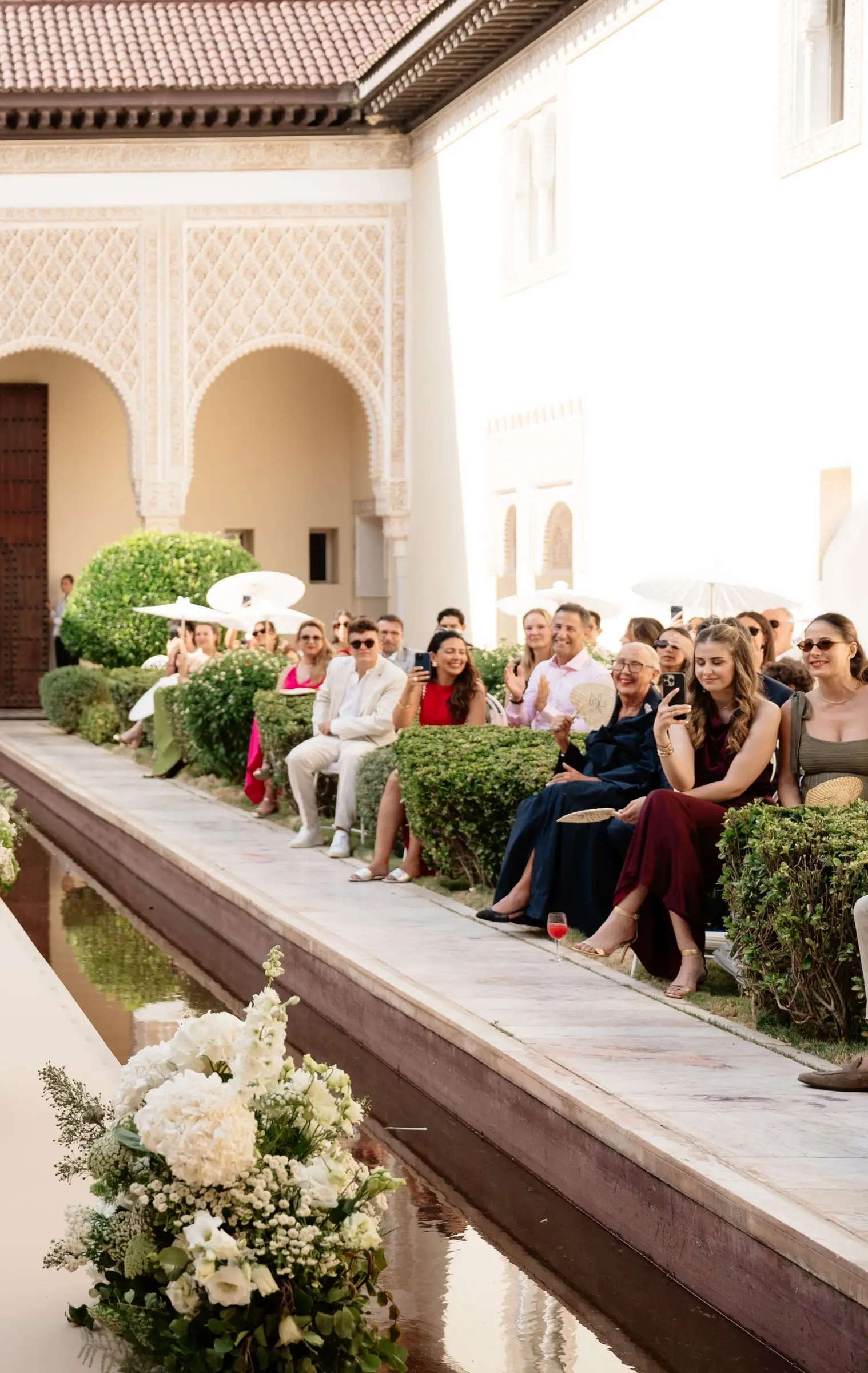 Guests seated along the water basin in the courtyard
