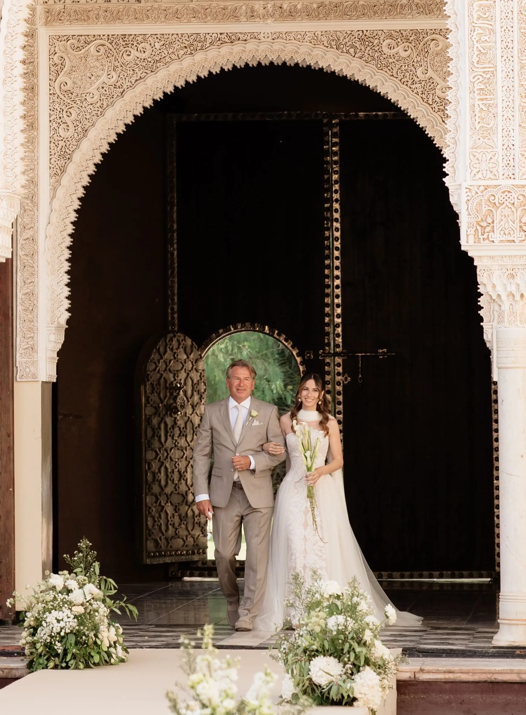 Bride entering with her father through the carved Moorish arch