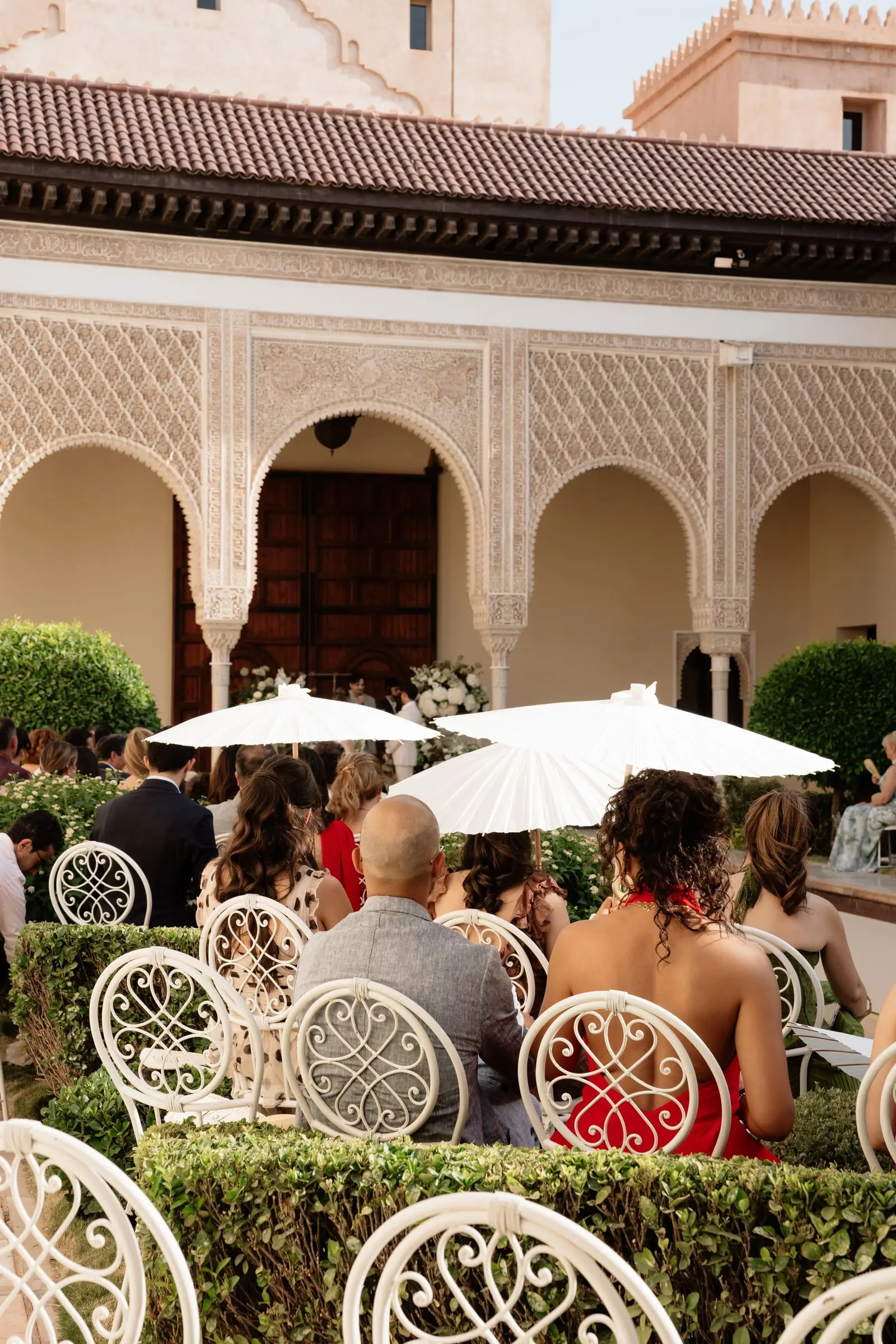 Guests with white parasols watching the ceremony
