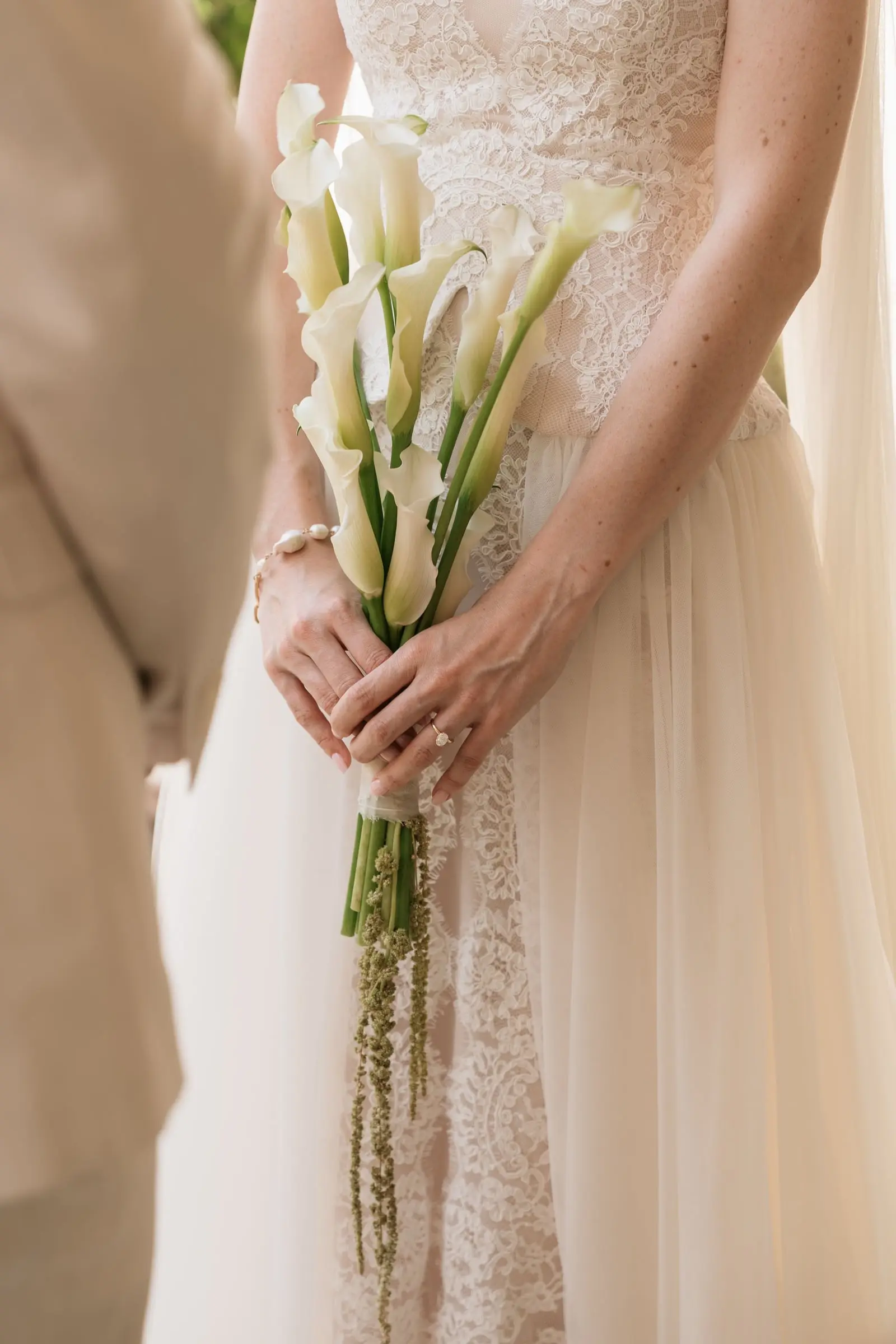 Bride holding a slim bouquet of calla lilies