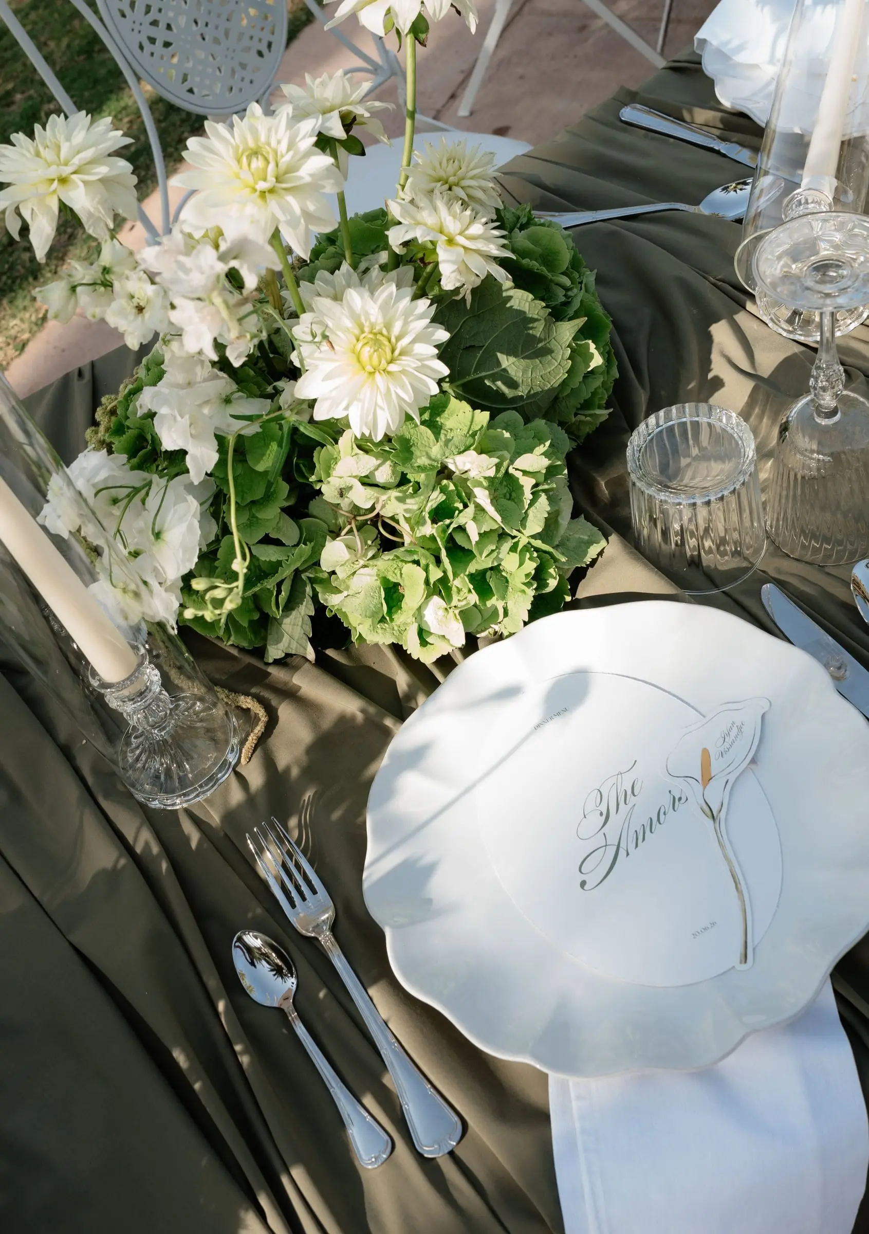 Table setting with white flowers, candles and a calligraphy menu