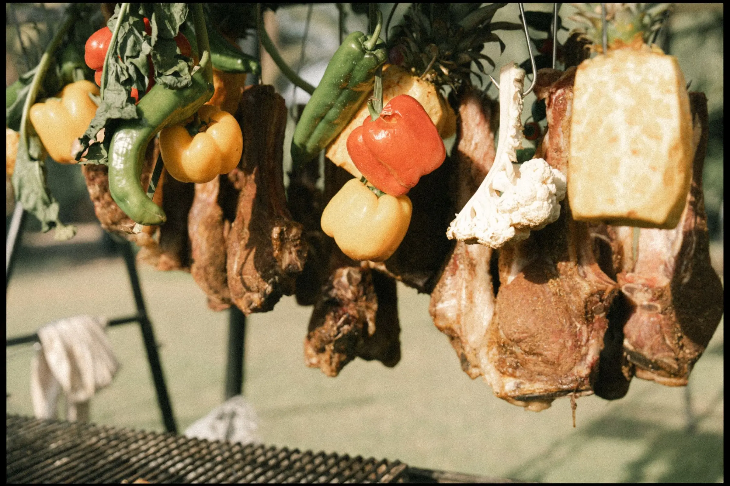 Grilled meat and vegetables hanging over the barbecue, on film