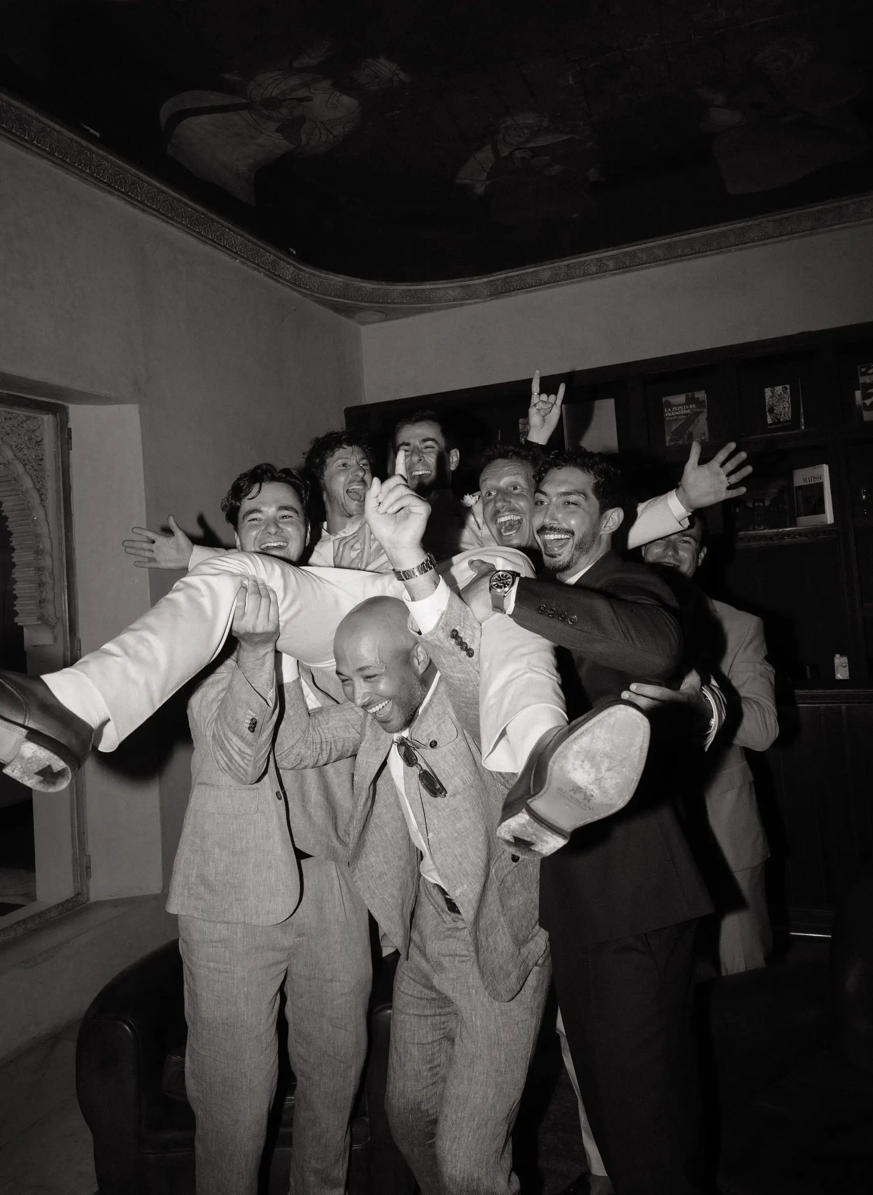 Black and white photo of the groomsmen lifting the groom
