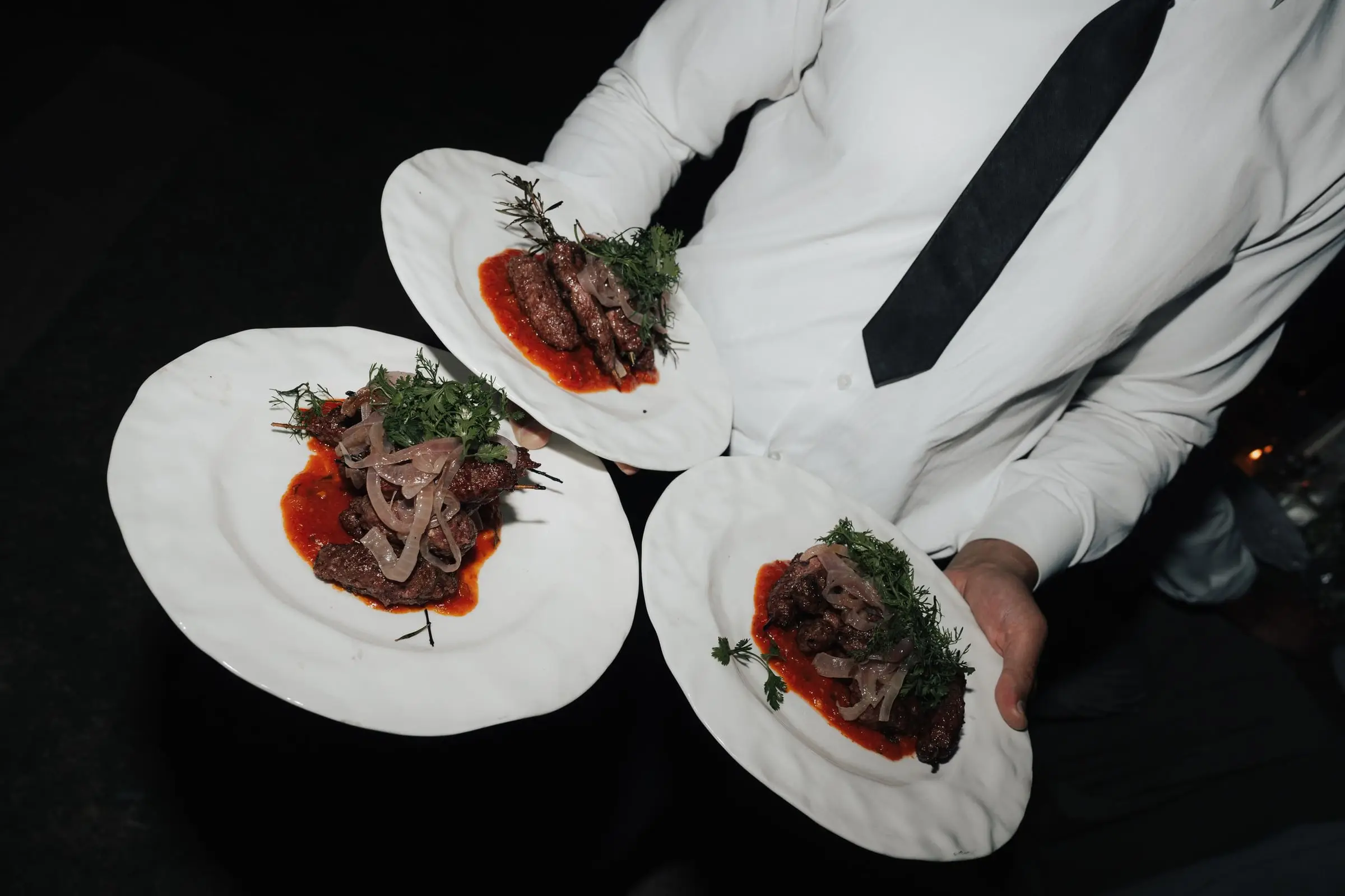 Waiter serving plates of lamb at the wedding dinner