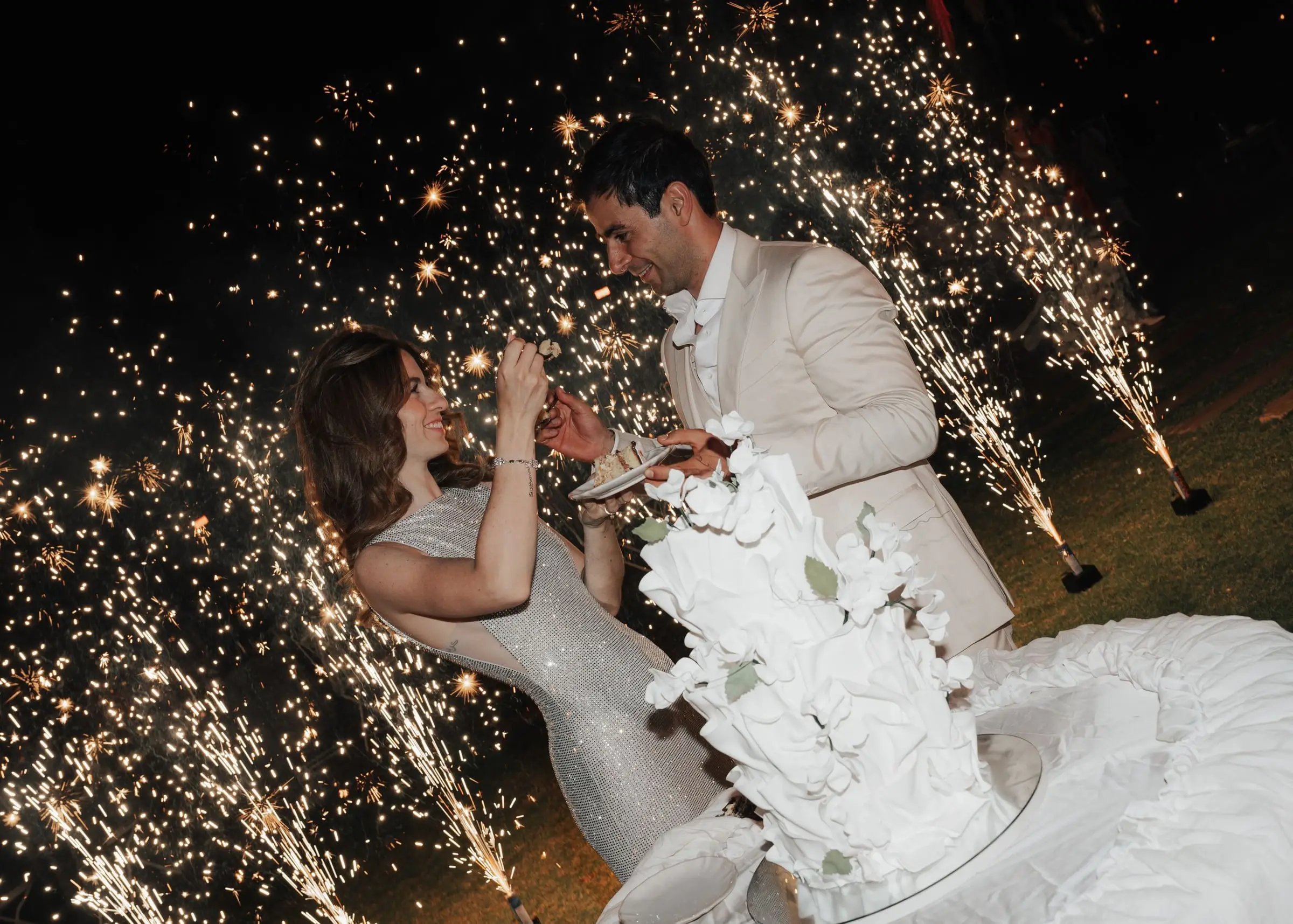 Couple cutting the wedding cake between sparklers