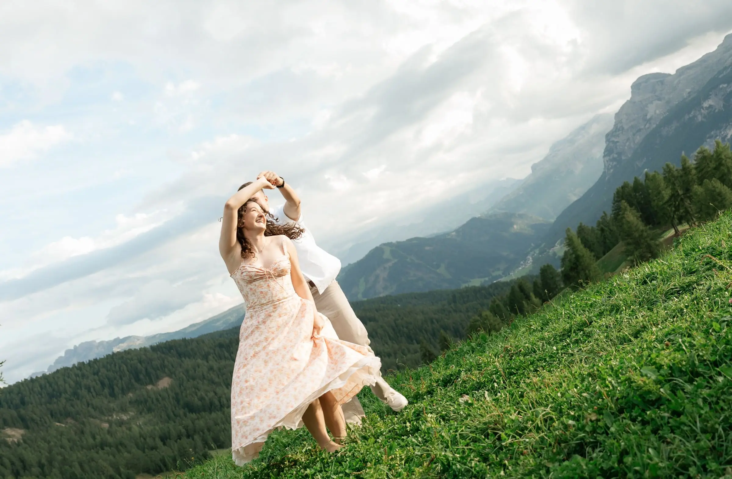 Woman in a floral dress twirling on a steep meadow in Val Badia