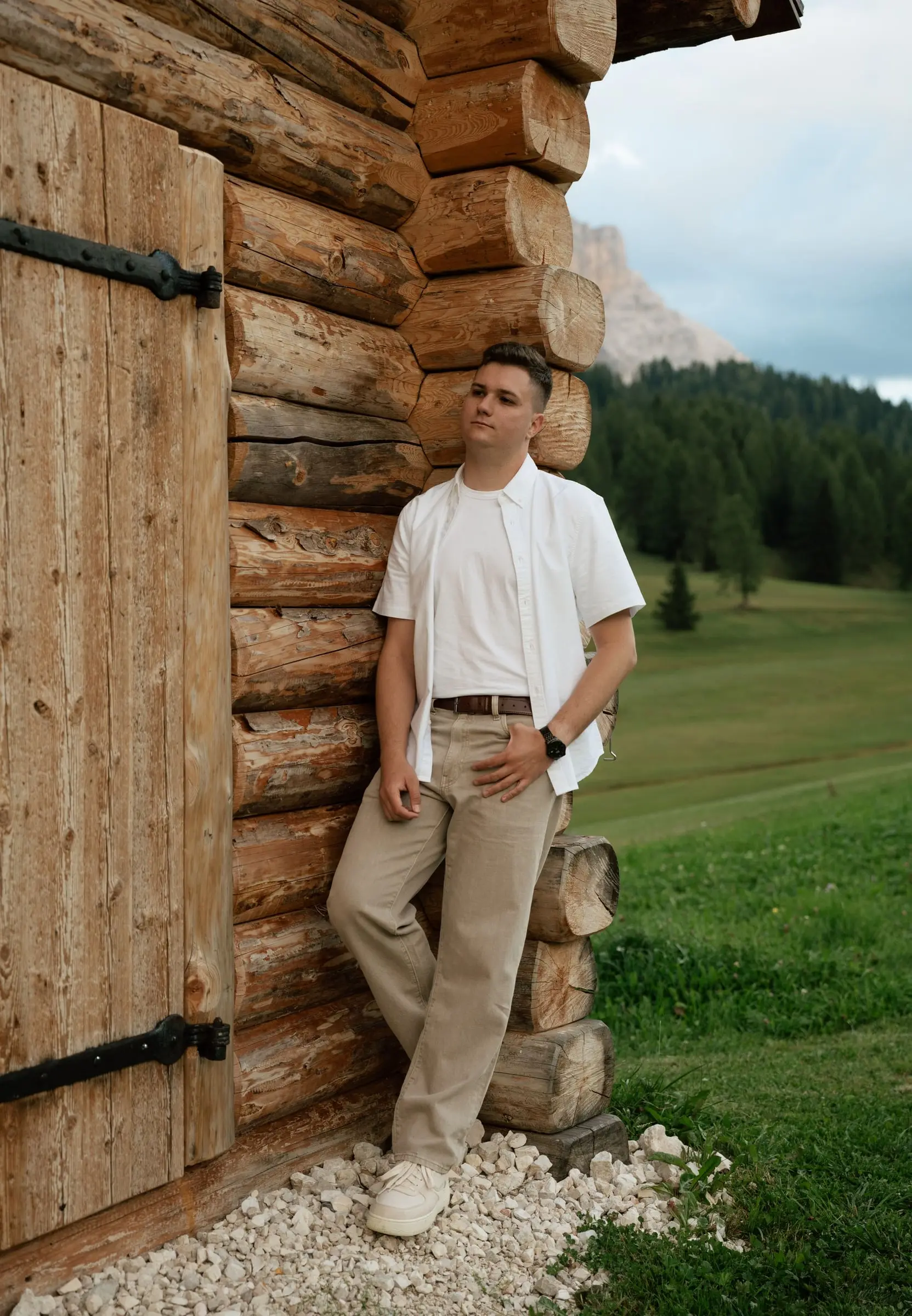 Man leaning against an old wooden hut in the Dolomites