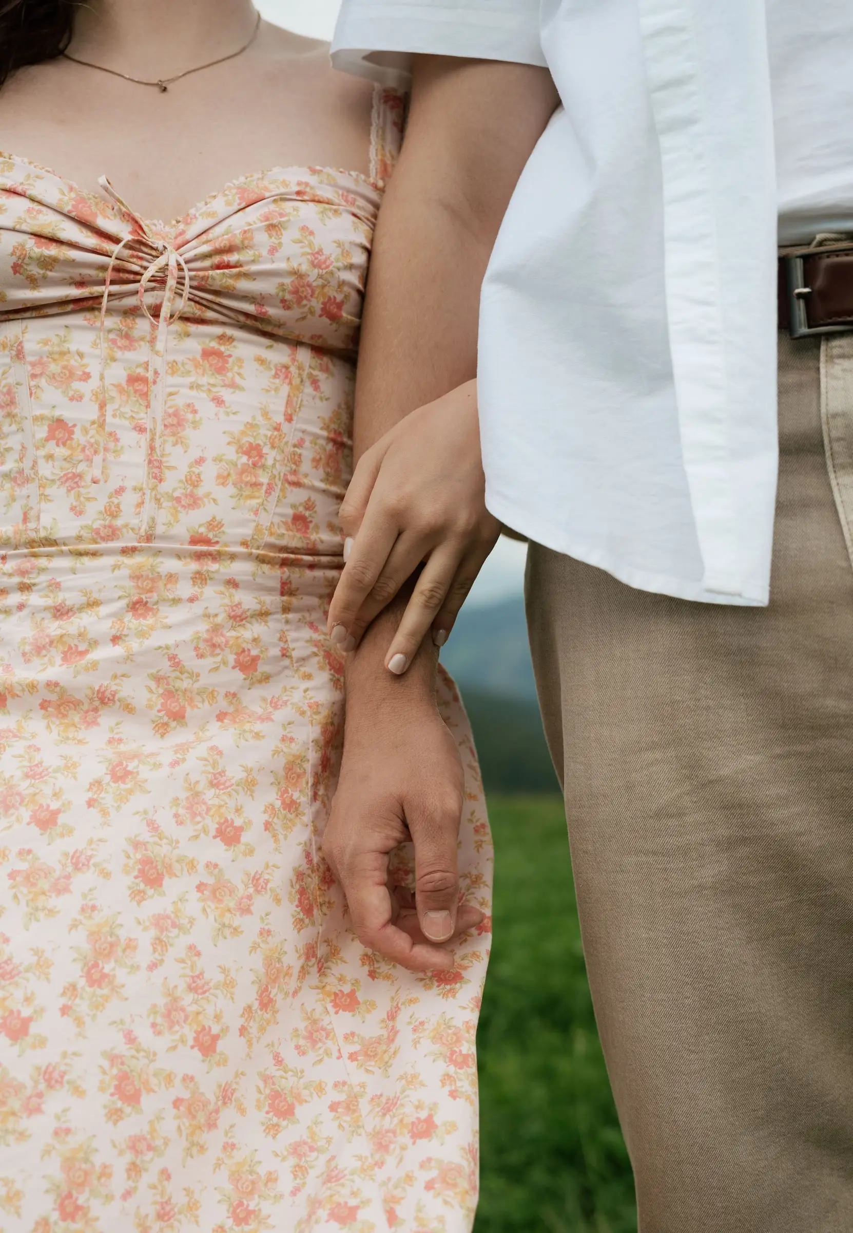 Close-up of her hand on his arm, floral summer dress