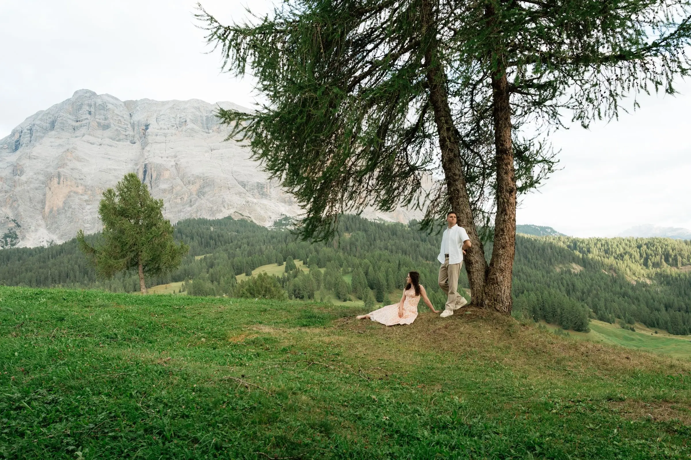 Couple under a larch tree in a green meadow below the Sas dla Crusc