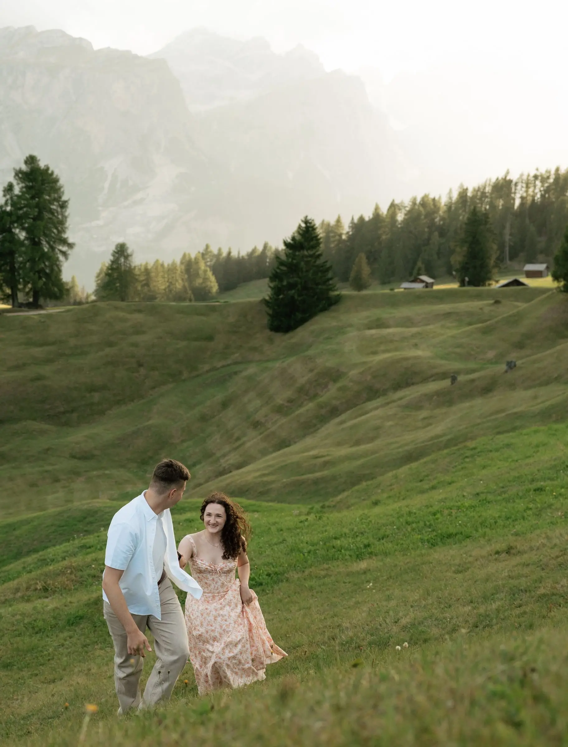 Couple walking up a green slope in La Val with pale rock walls behind