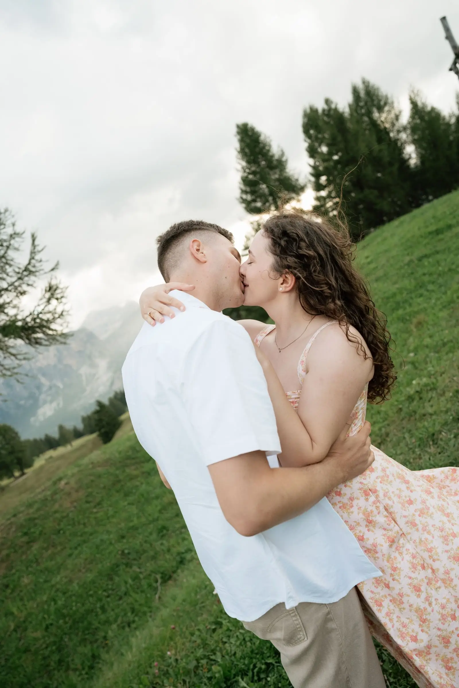 Couple kissing on a grassy slope in the Dolomites