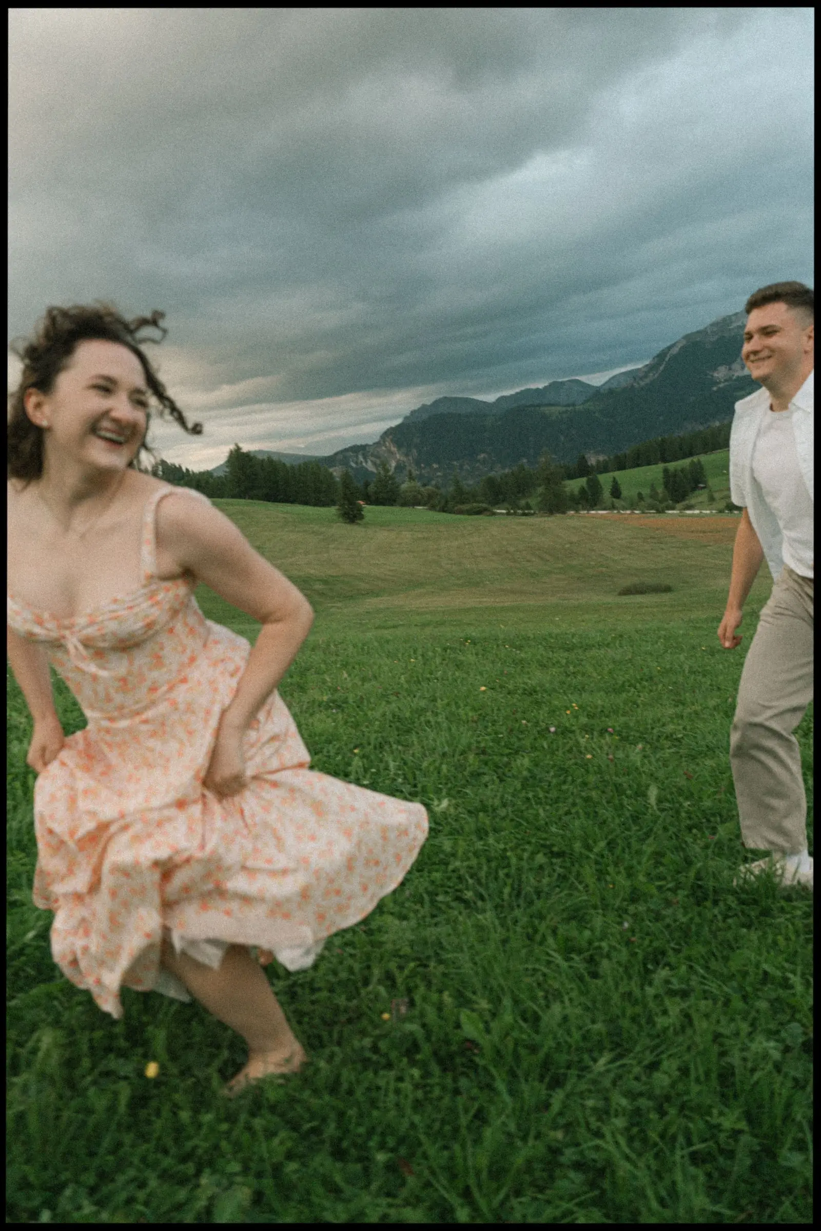 She laughs as she runs across the meadow, storm clouds over the mountains