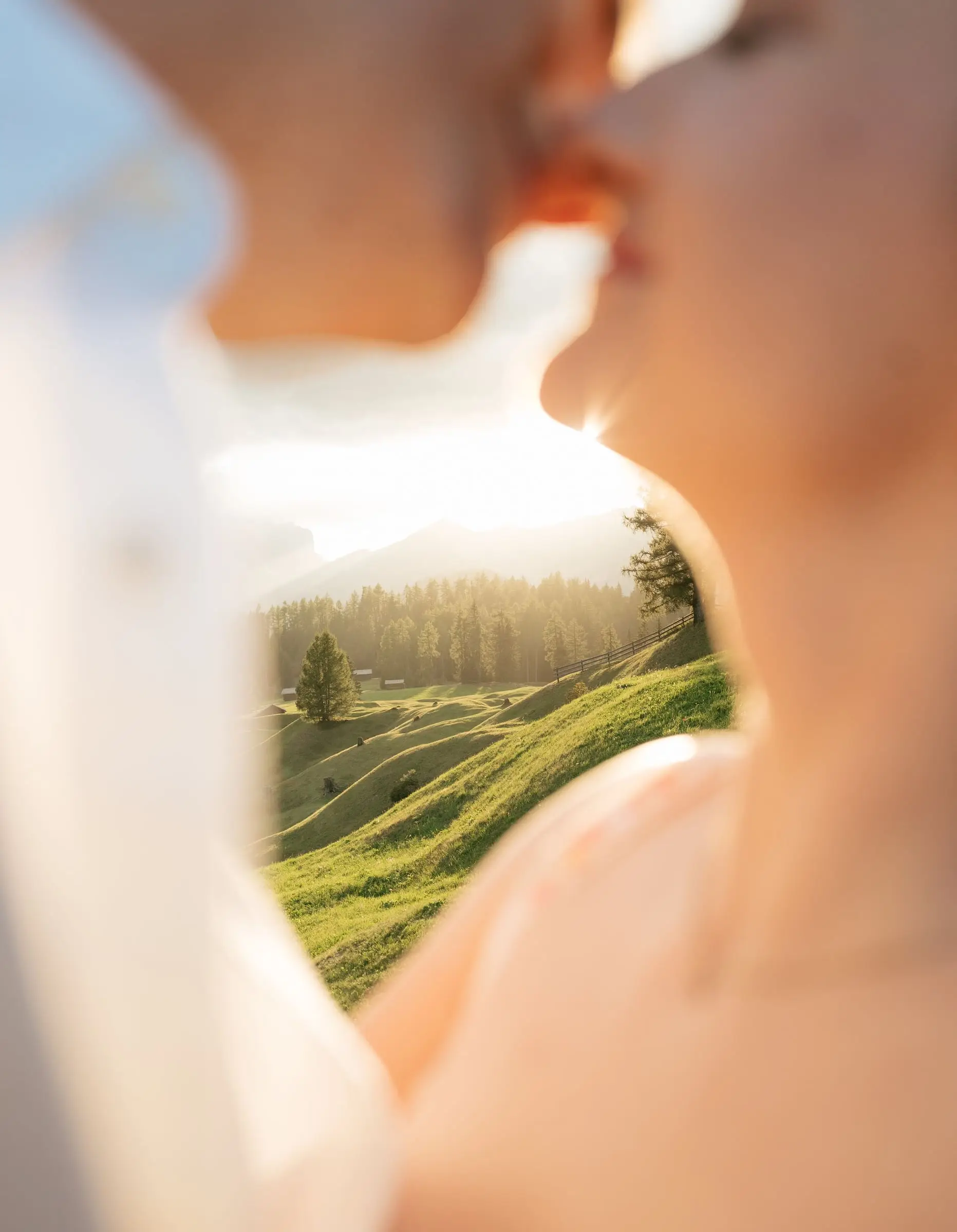 Close-up of the couple kissing, the valley glowing behind them