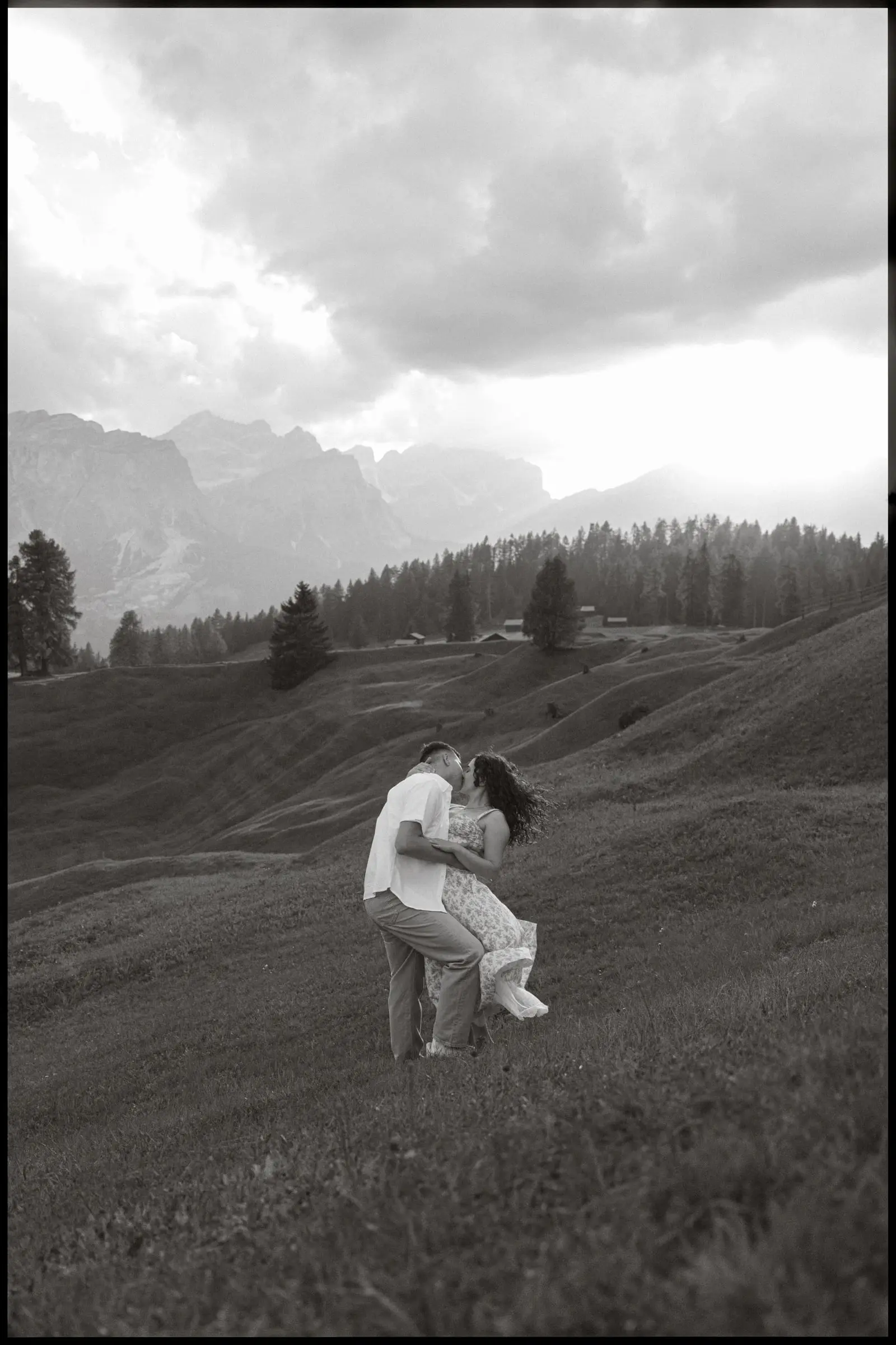 Black and white photo of the couple kissing in the meadow