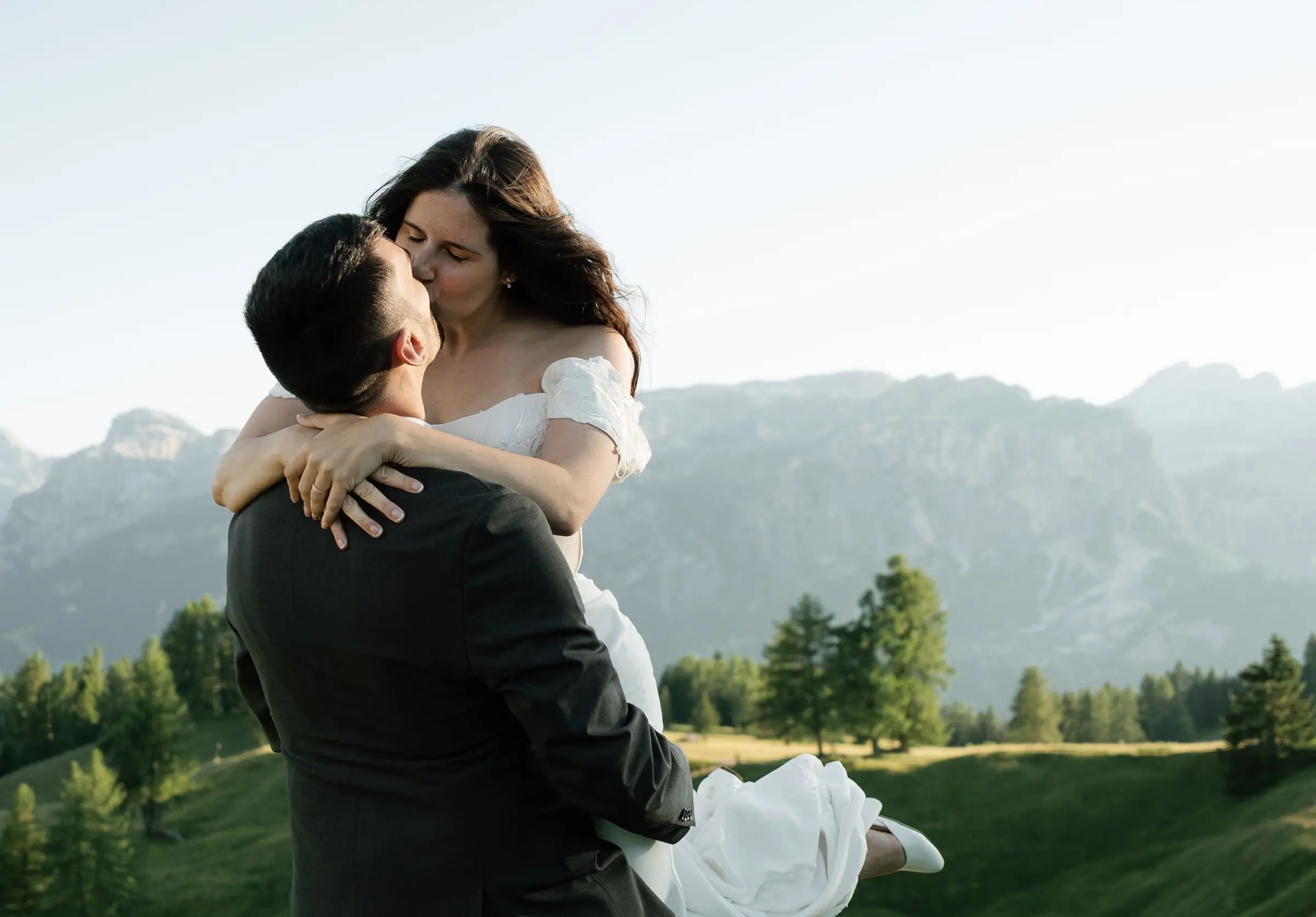 Groom lifts the bride and they kiss with the Dolomites behind