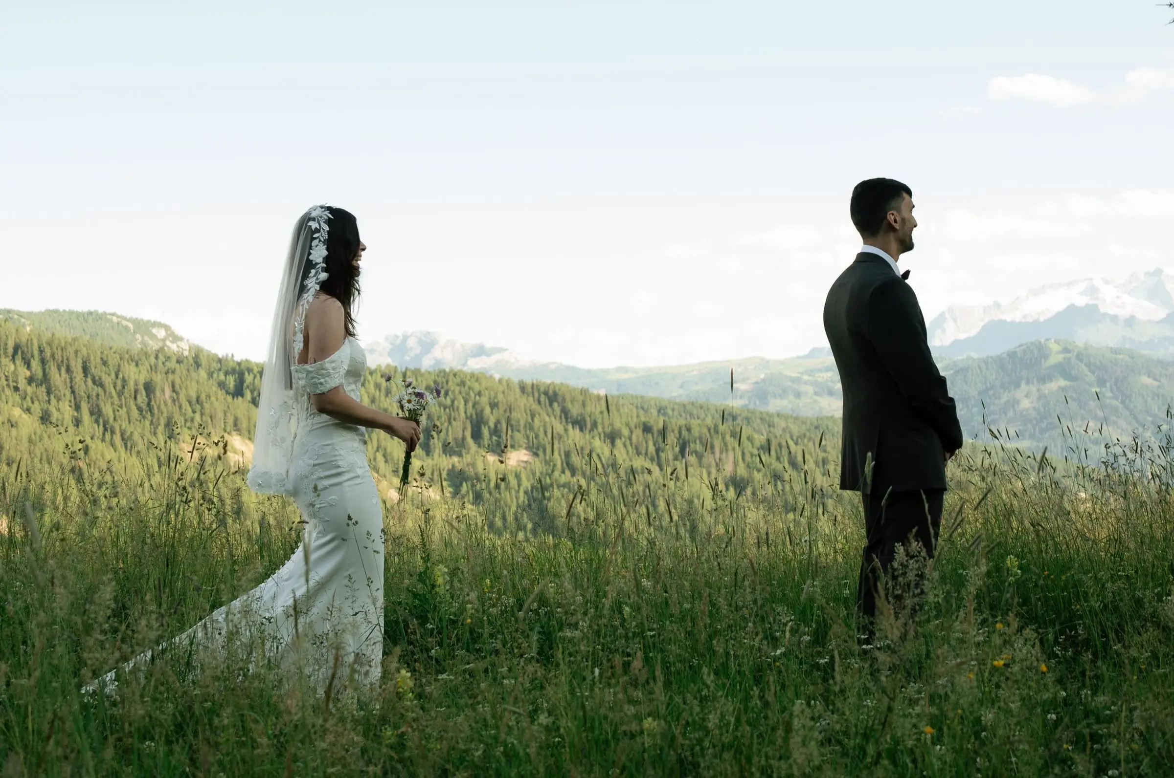 Bride walking towards the groom for their first look in an alpine meadow