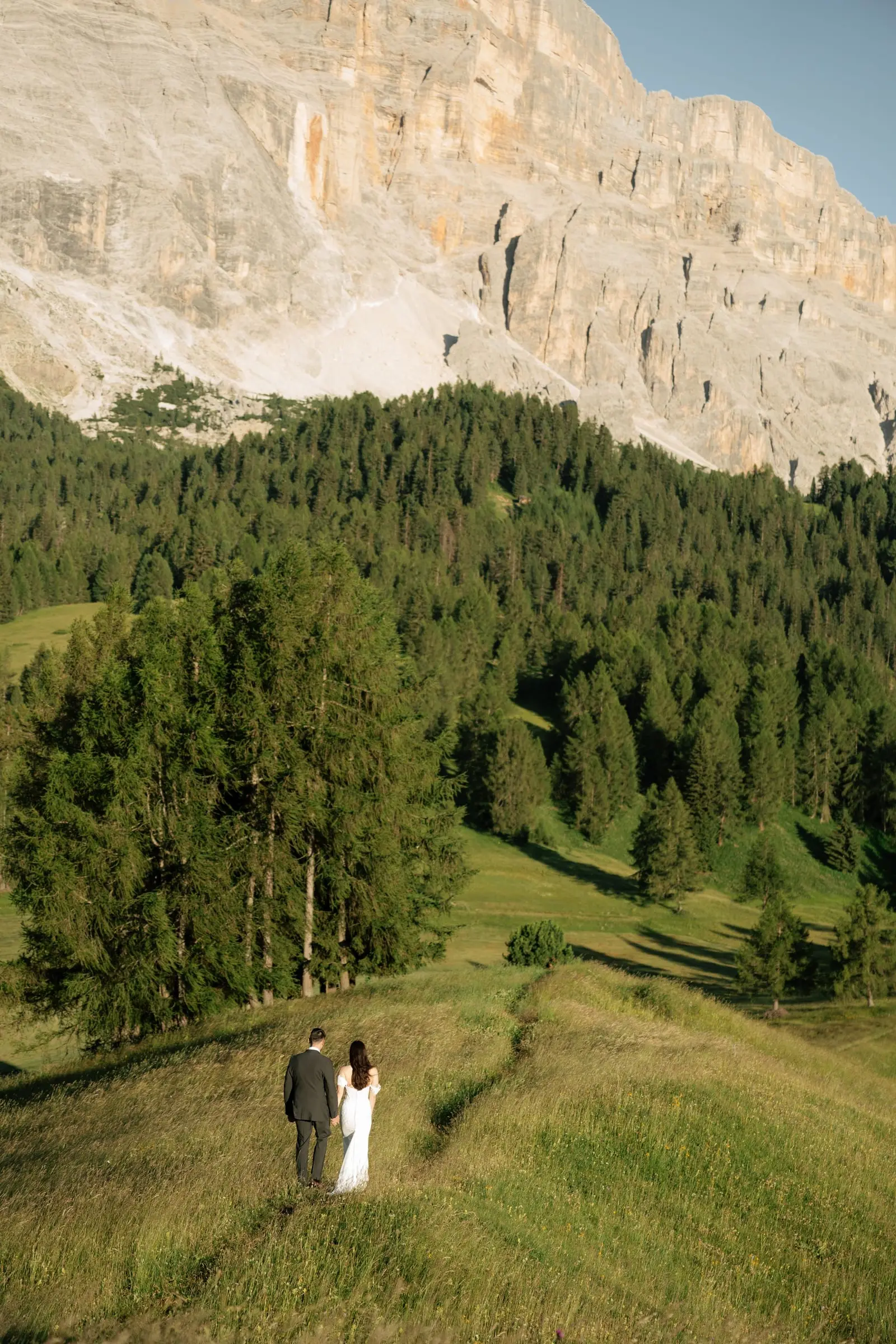 Bride and groom walking a path below the Sas dla Crusc in Val Badia