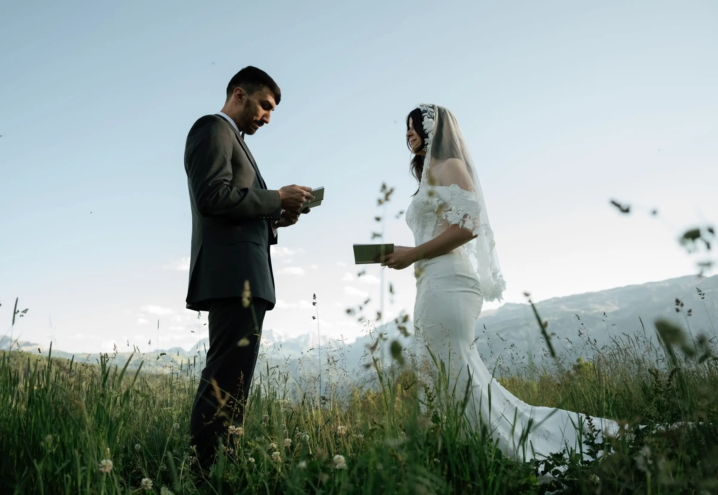 Bride and groom exchanging vows in the tall grass of a mountain meadow