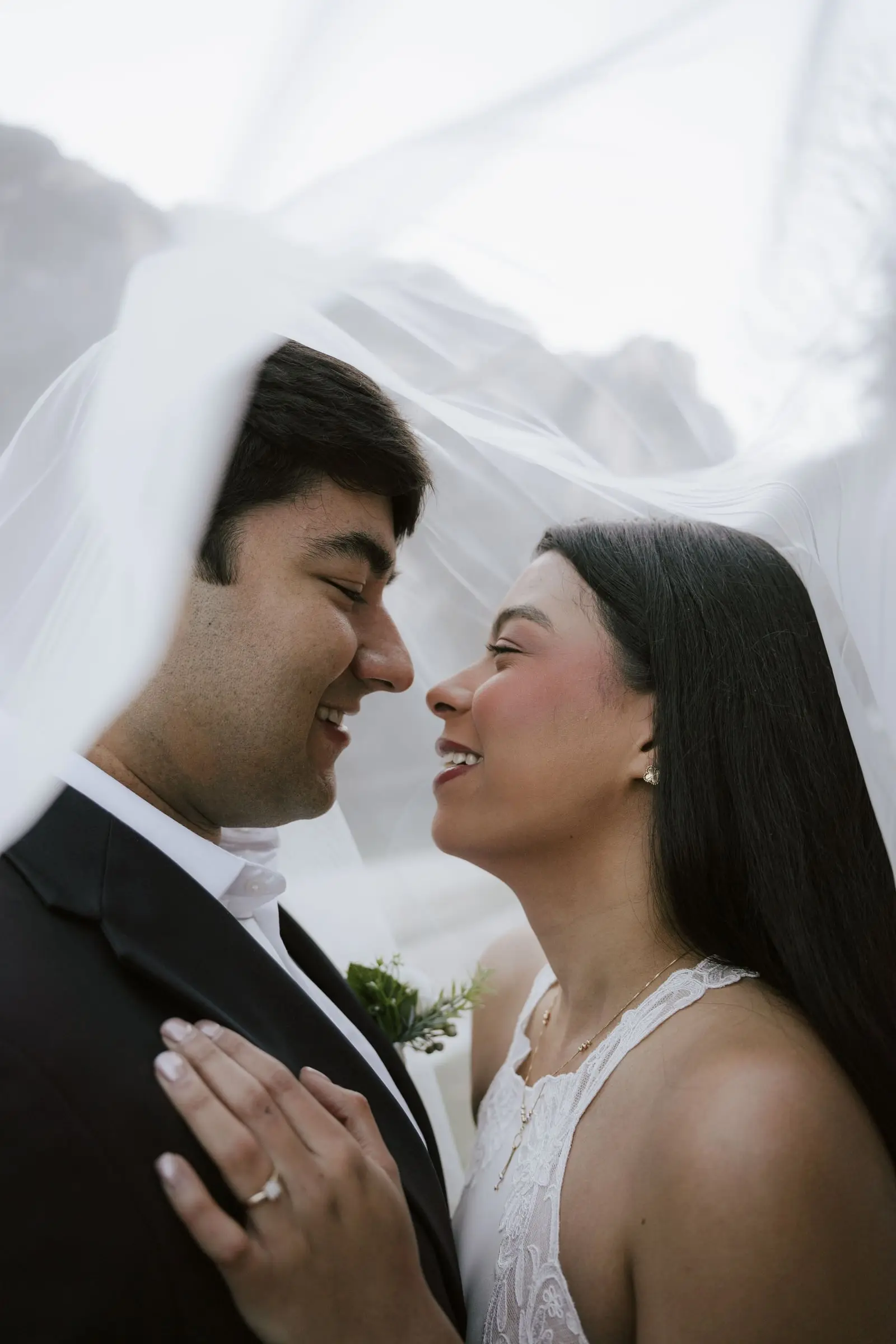 Couple smiling at each other under a veil