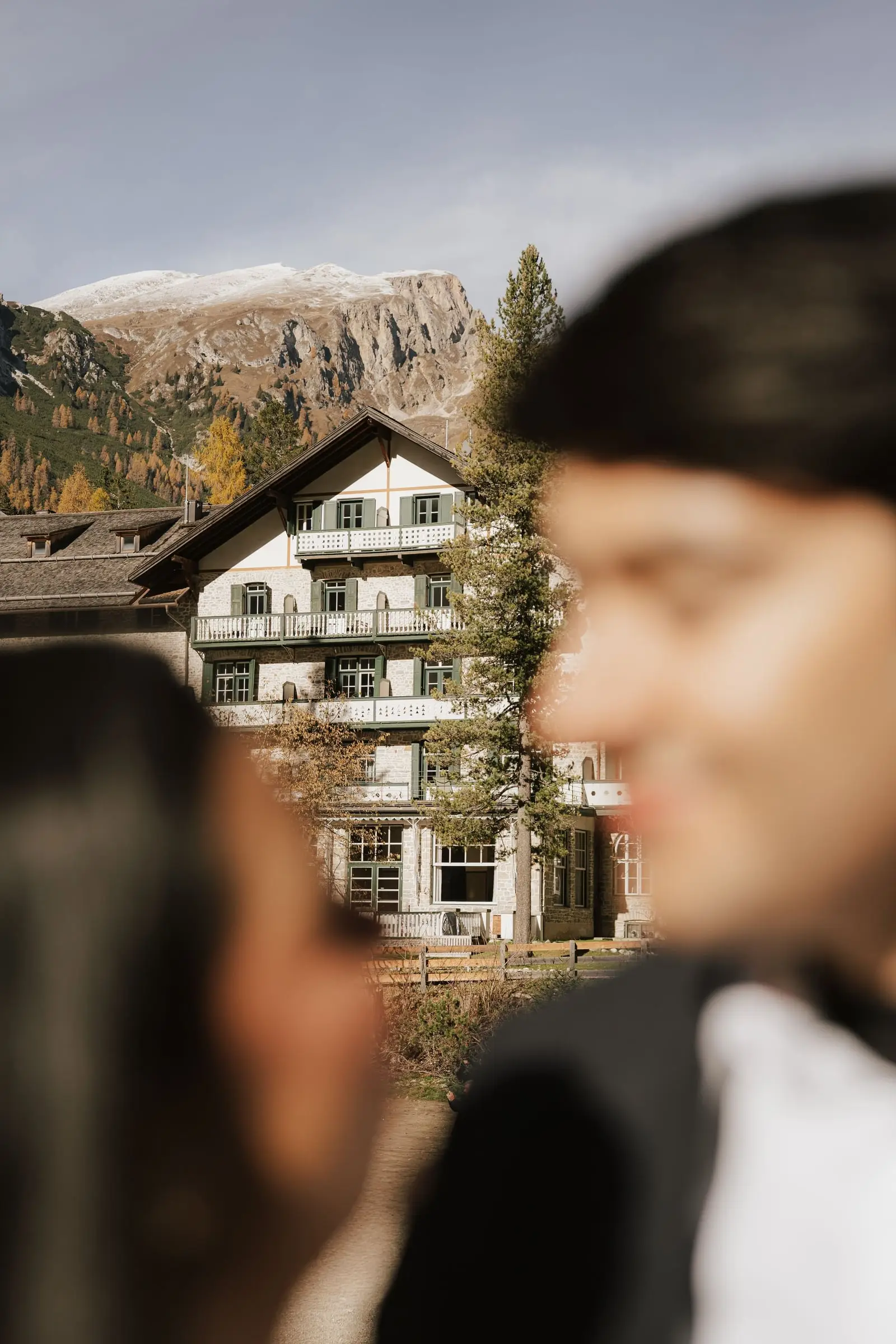 Couple in the foreground with the historic Hotel Lago di Braies behind