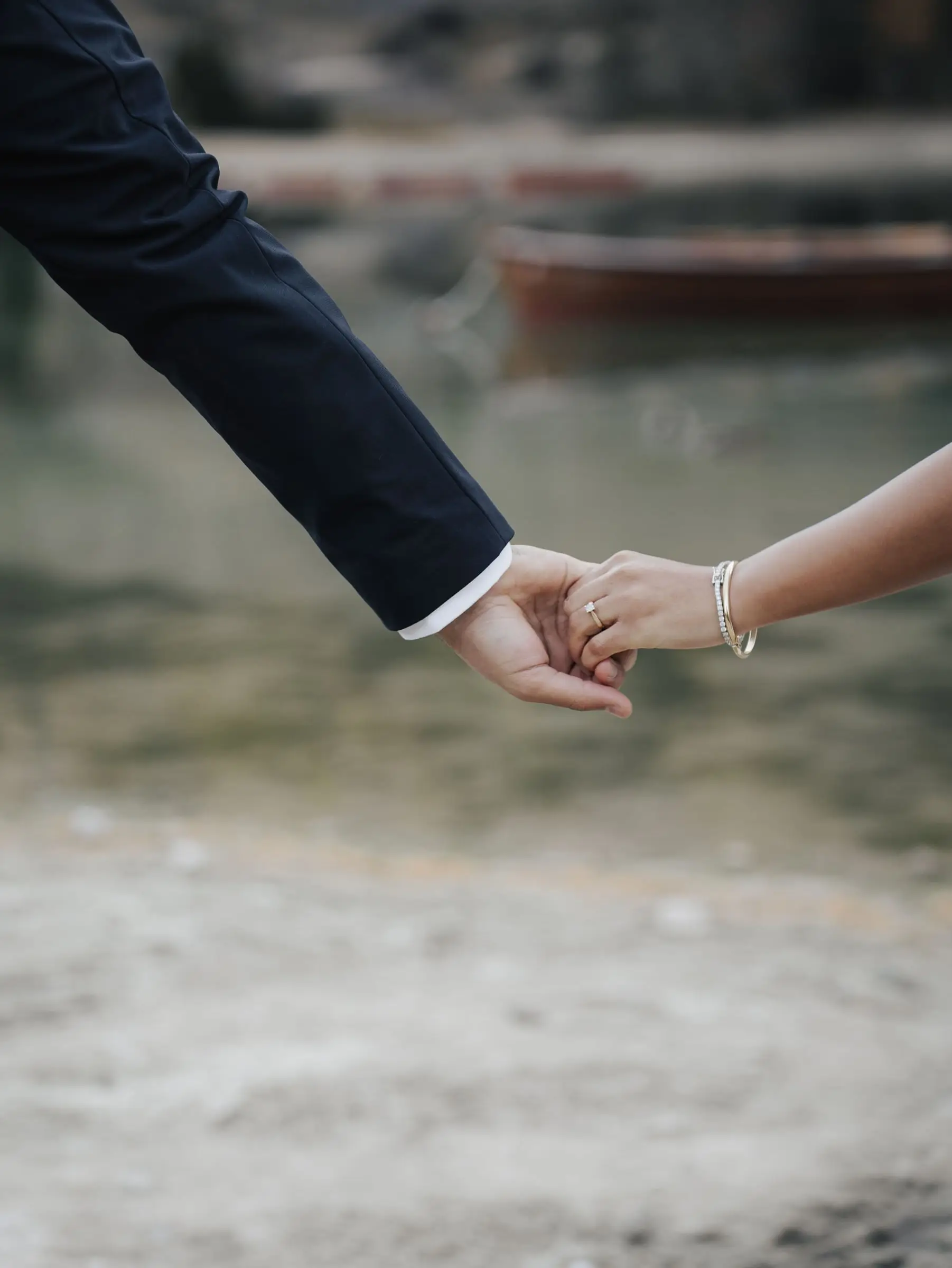 Close-up of the couple holding hands, the lake blurred behind them