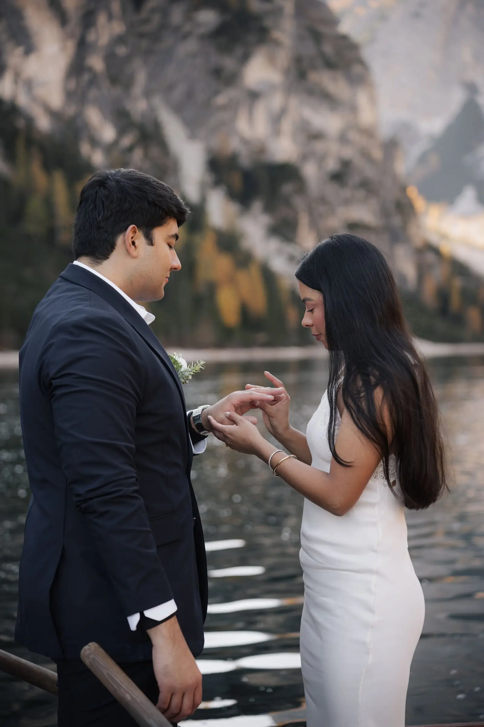 He puts a ring on her finger by the lake, golden larches behind
