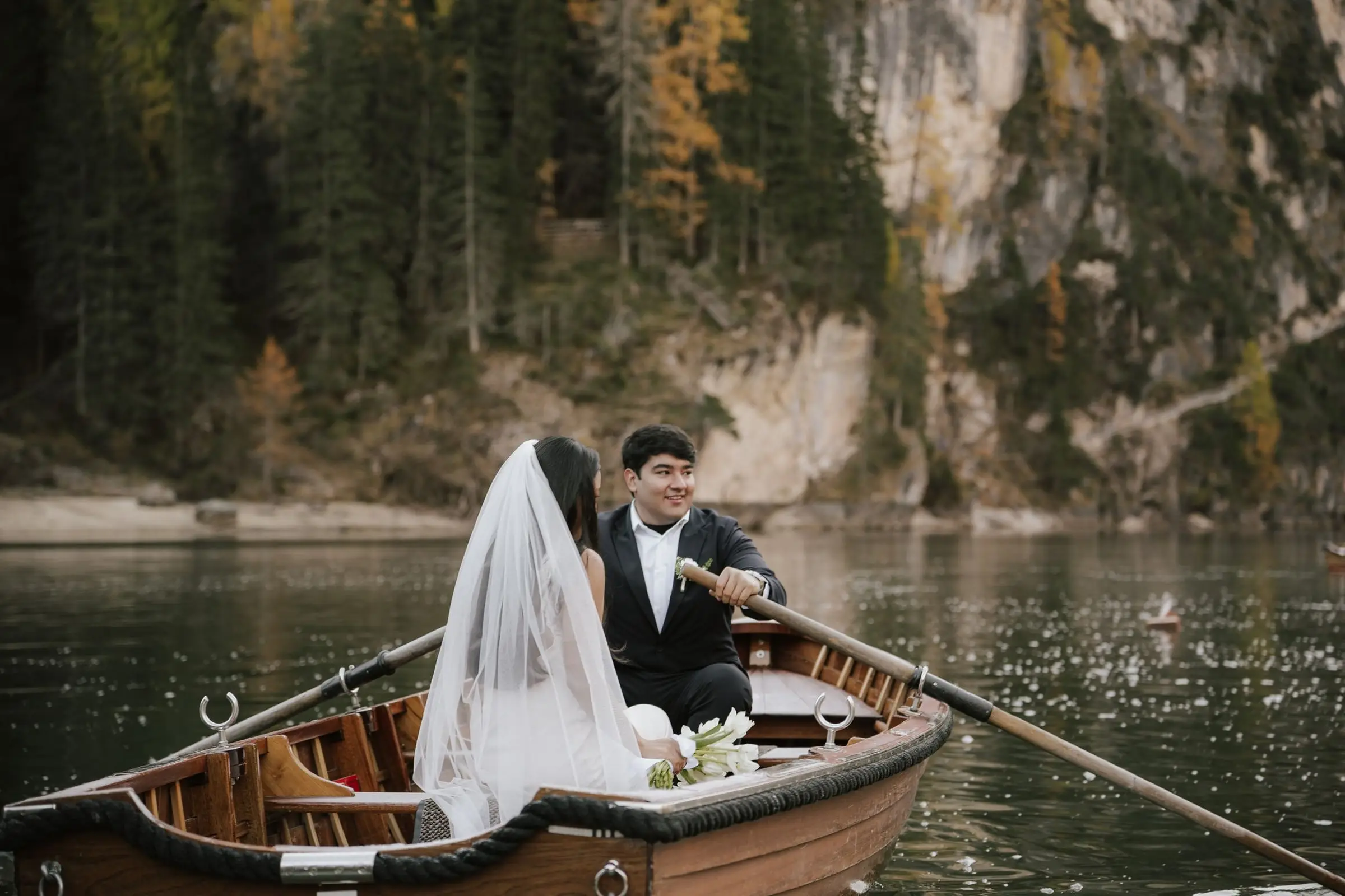 Couple in a veil and suit sitting in a rowing boat on Lago di Braies