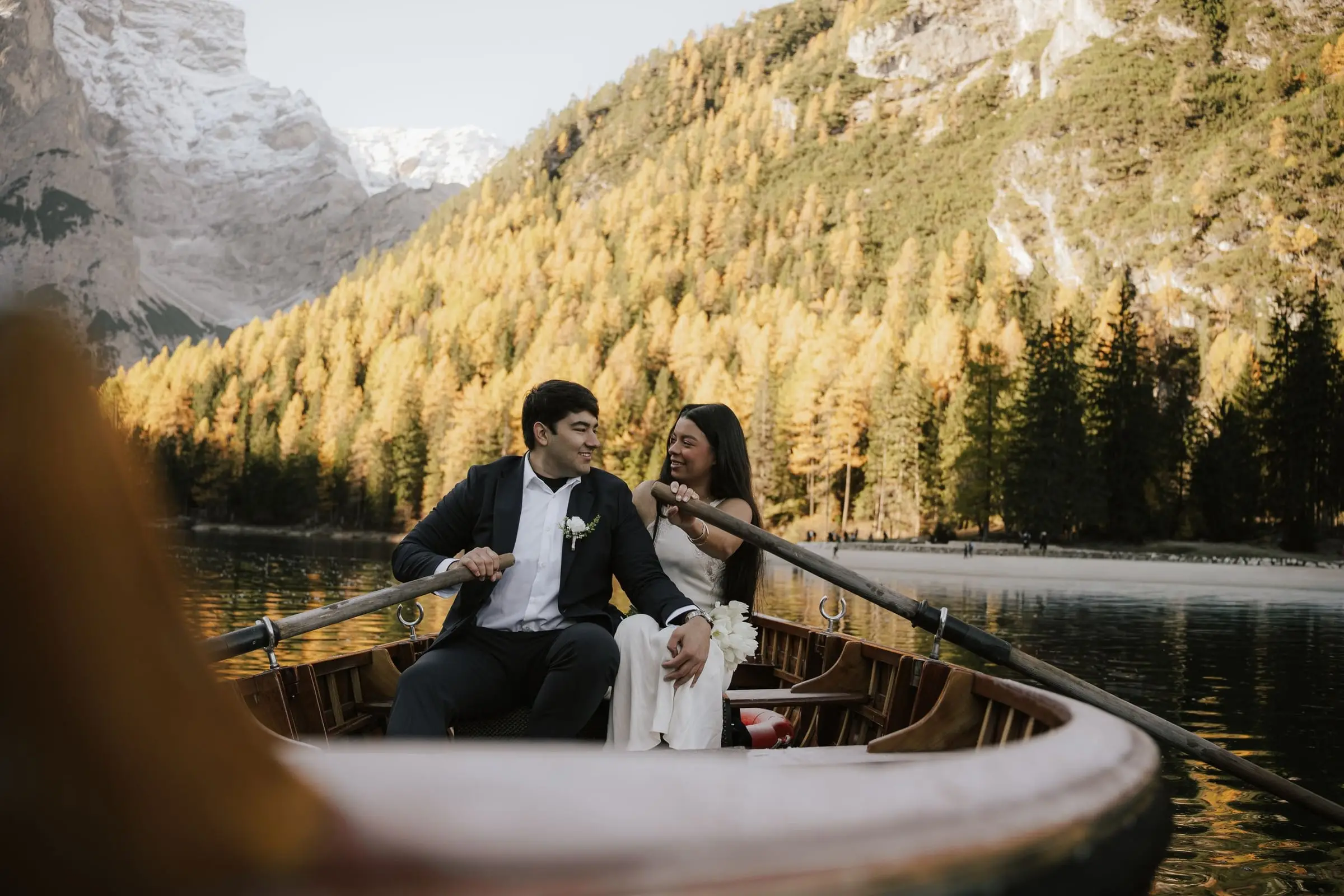 Couple laughing in a rowing boat among golden autumn larches