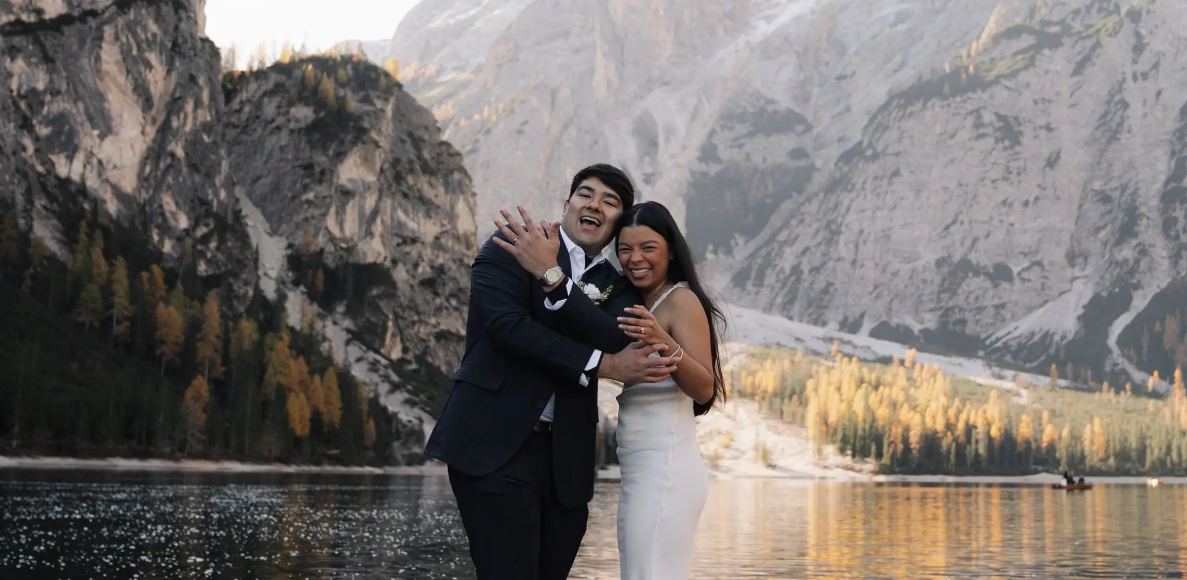 Couple hugging and laughing by the lake in autumn light