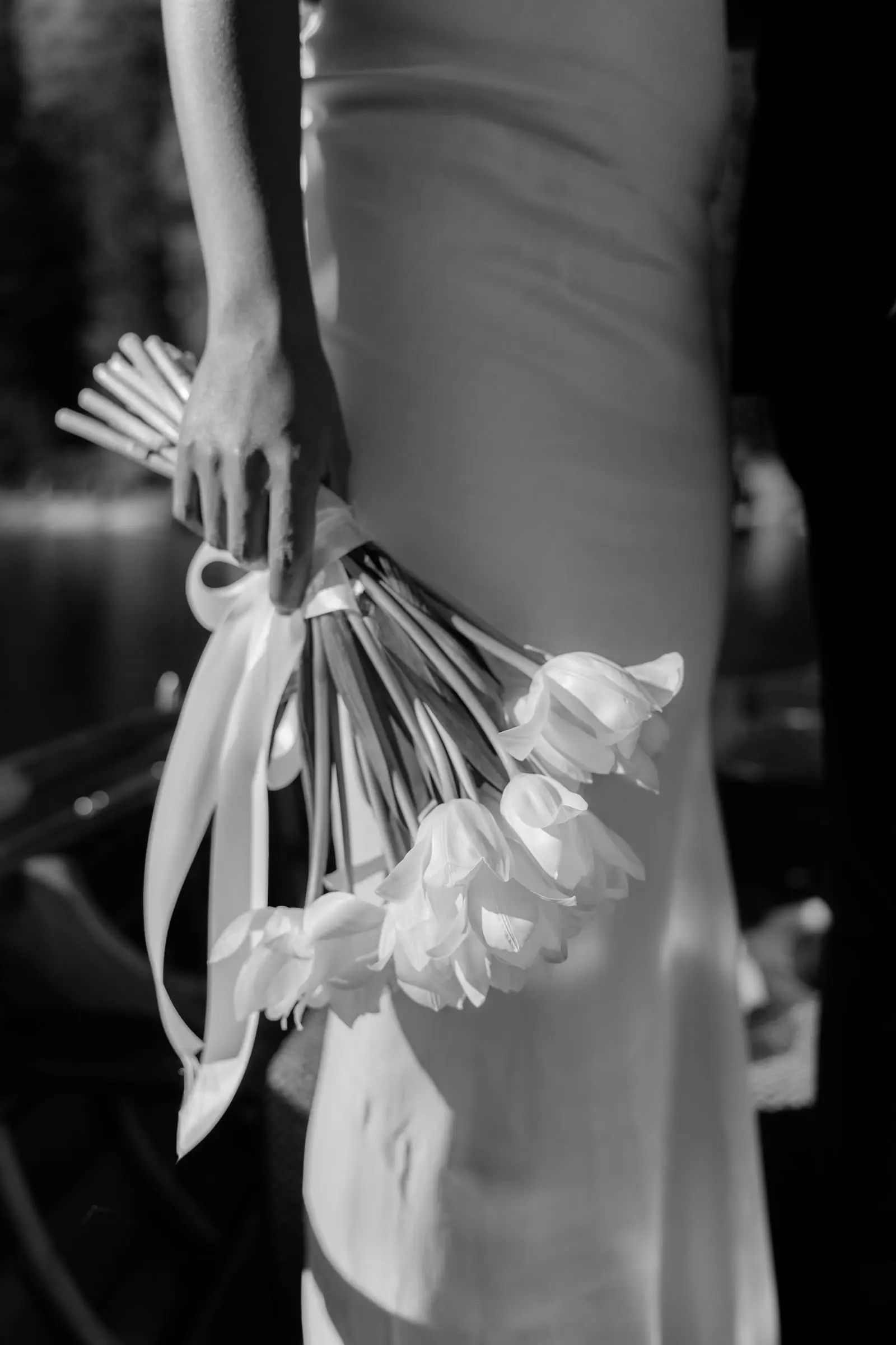 Black and white detail of her white calla bouquet with ribbons