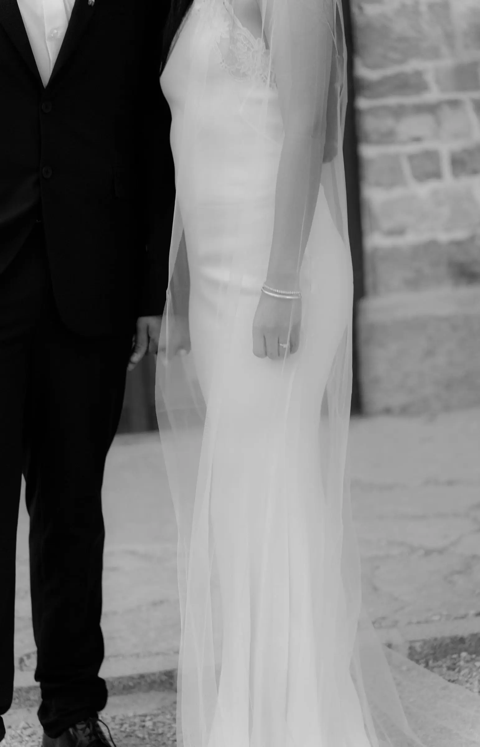 Black and white detail of his suit and her long veil