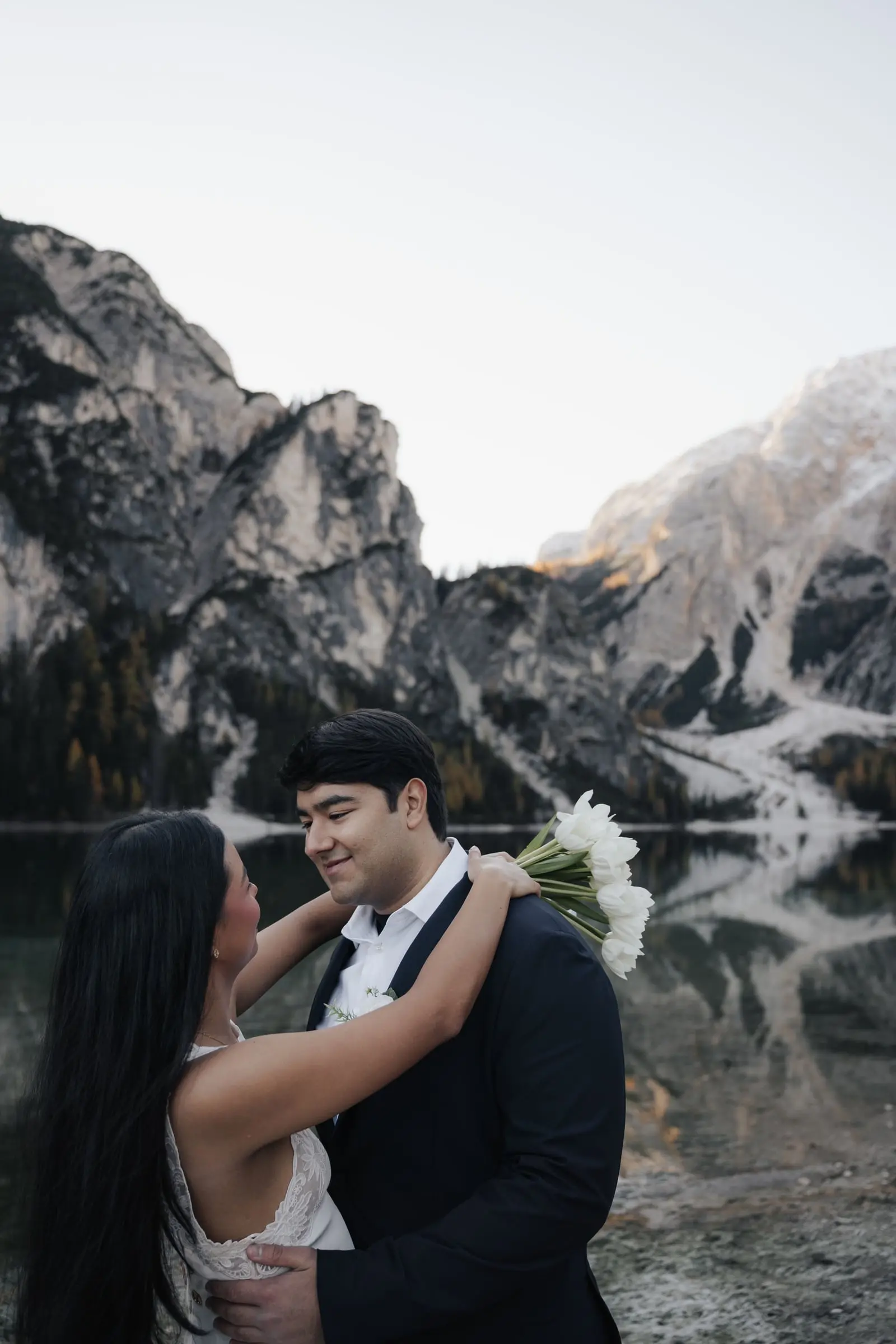 Couple embracing by the lake, dramatic rock walls behind