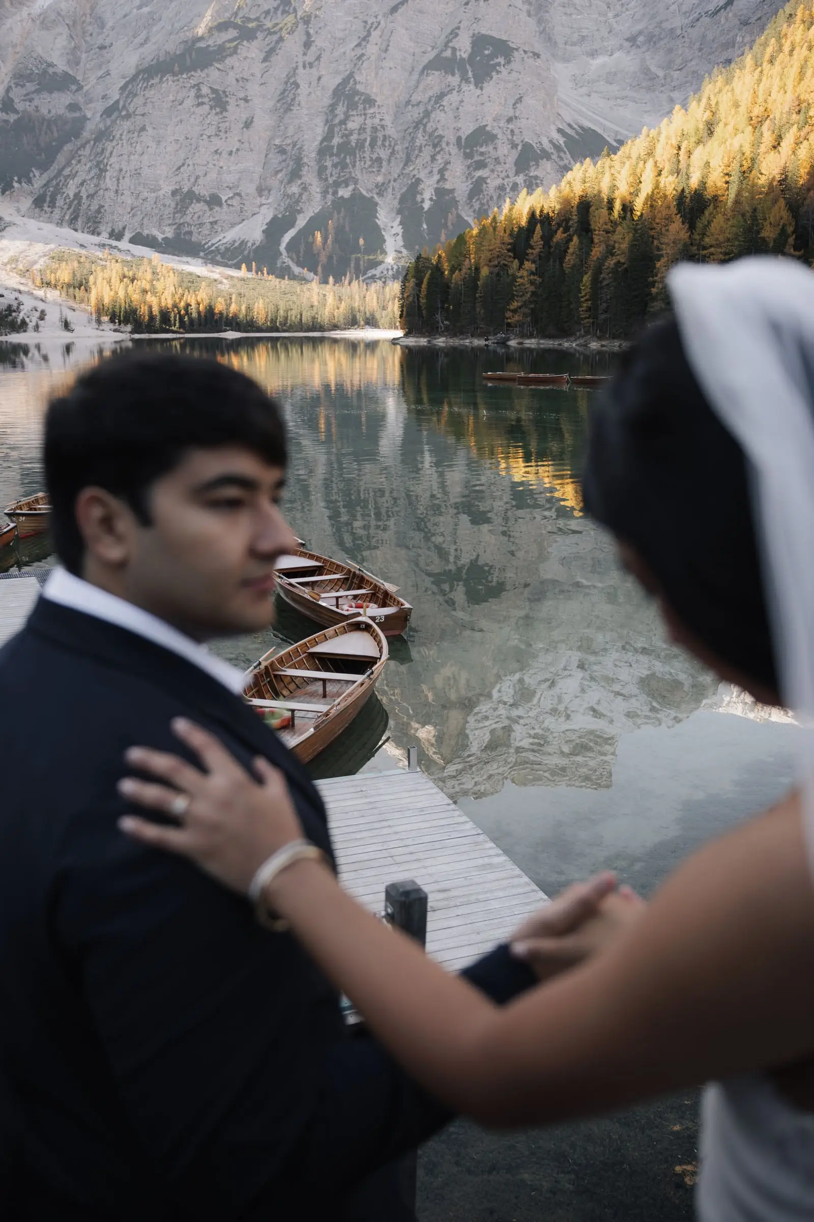Her hand on his shoulder at the boathouse, larches glowing behind