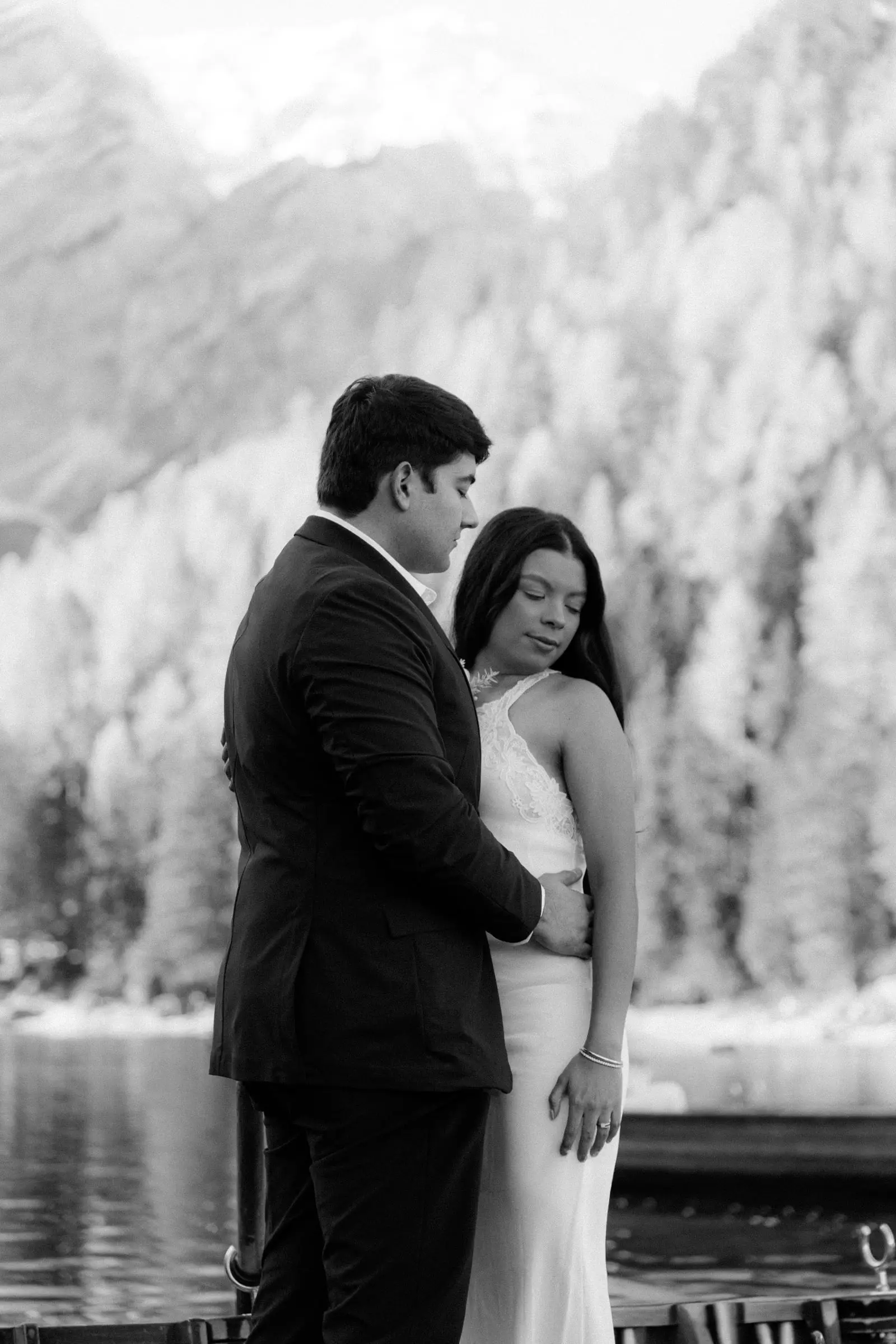 Black and white photo of the couple embracing by the lake