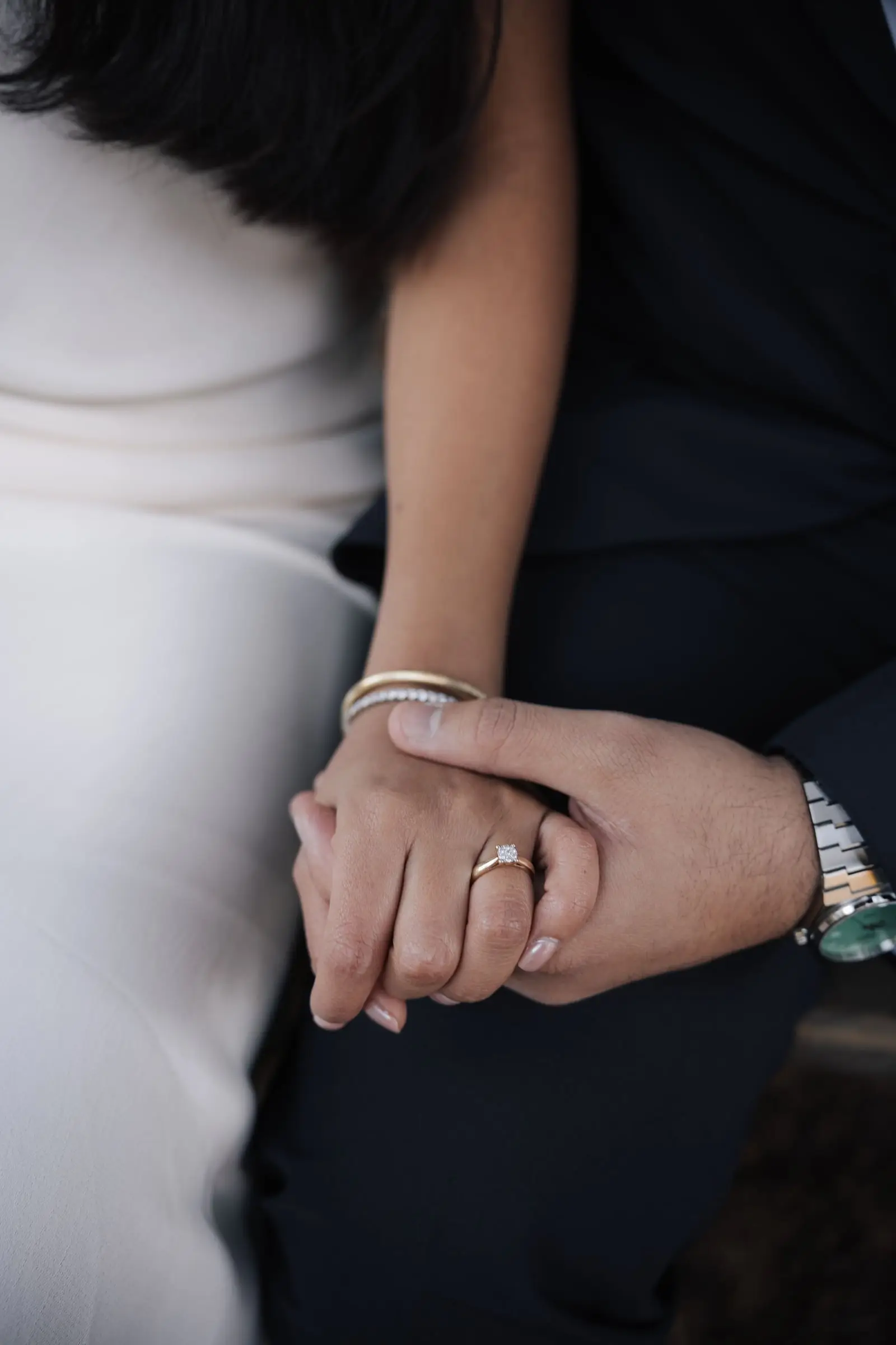 Close-up of their hands with the wedding ring and bracelets