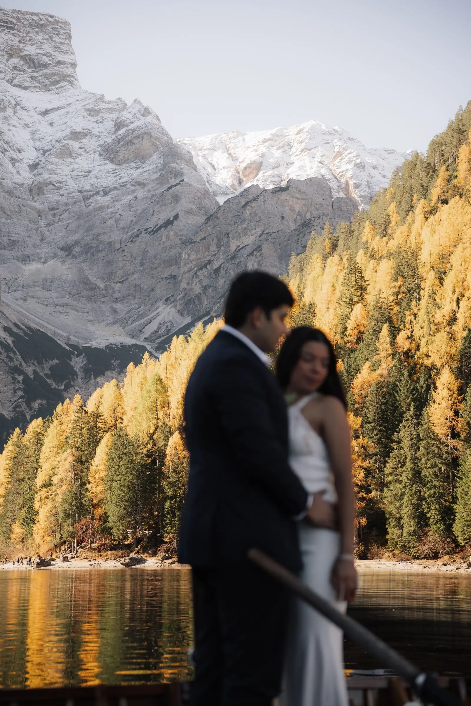 Couple embracing against golden larches and snowy peaks
