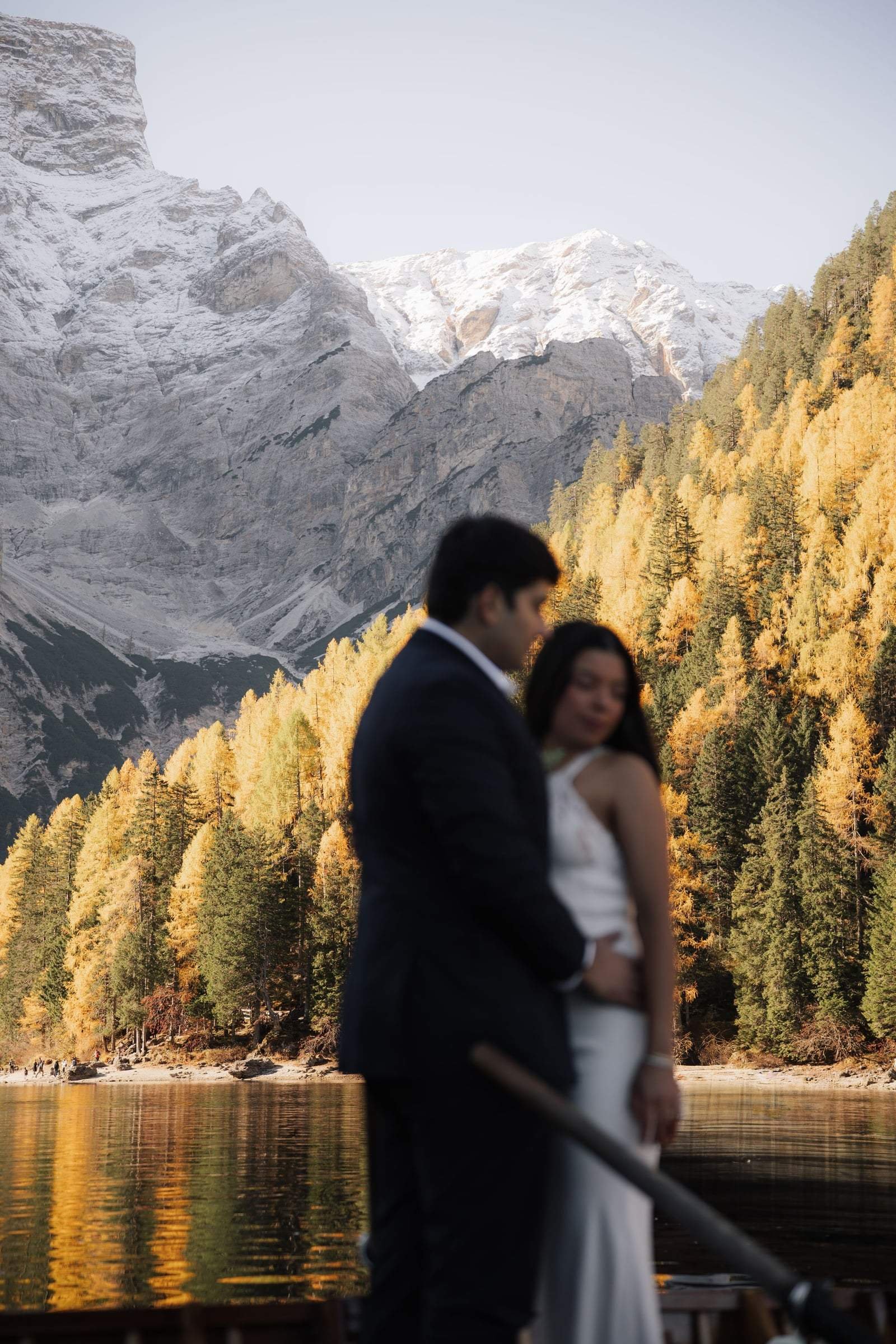Couple embracing against golden larches and snowy peaks