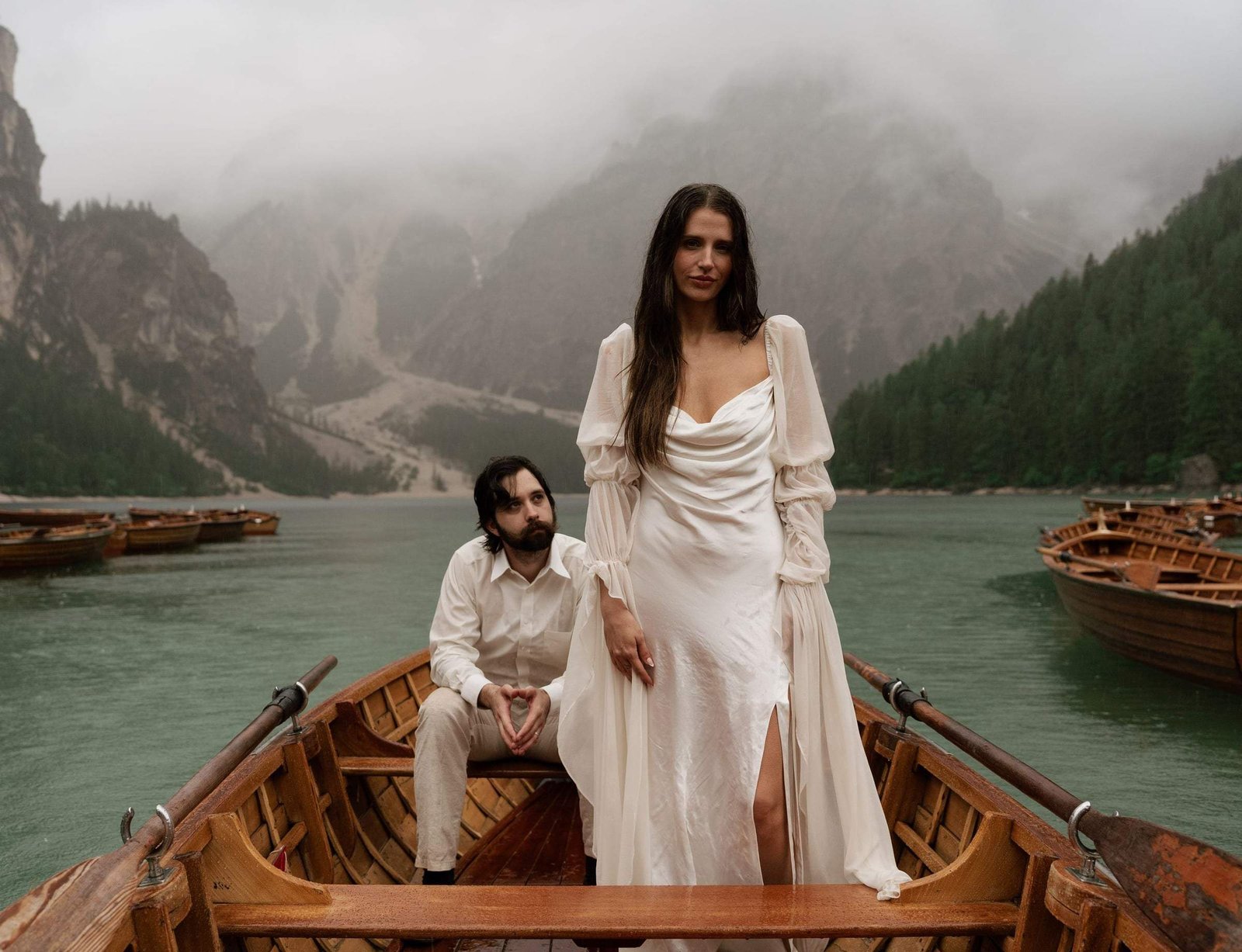 Bride standing in the rowing boat, the groom seated, cliffs in the mist