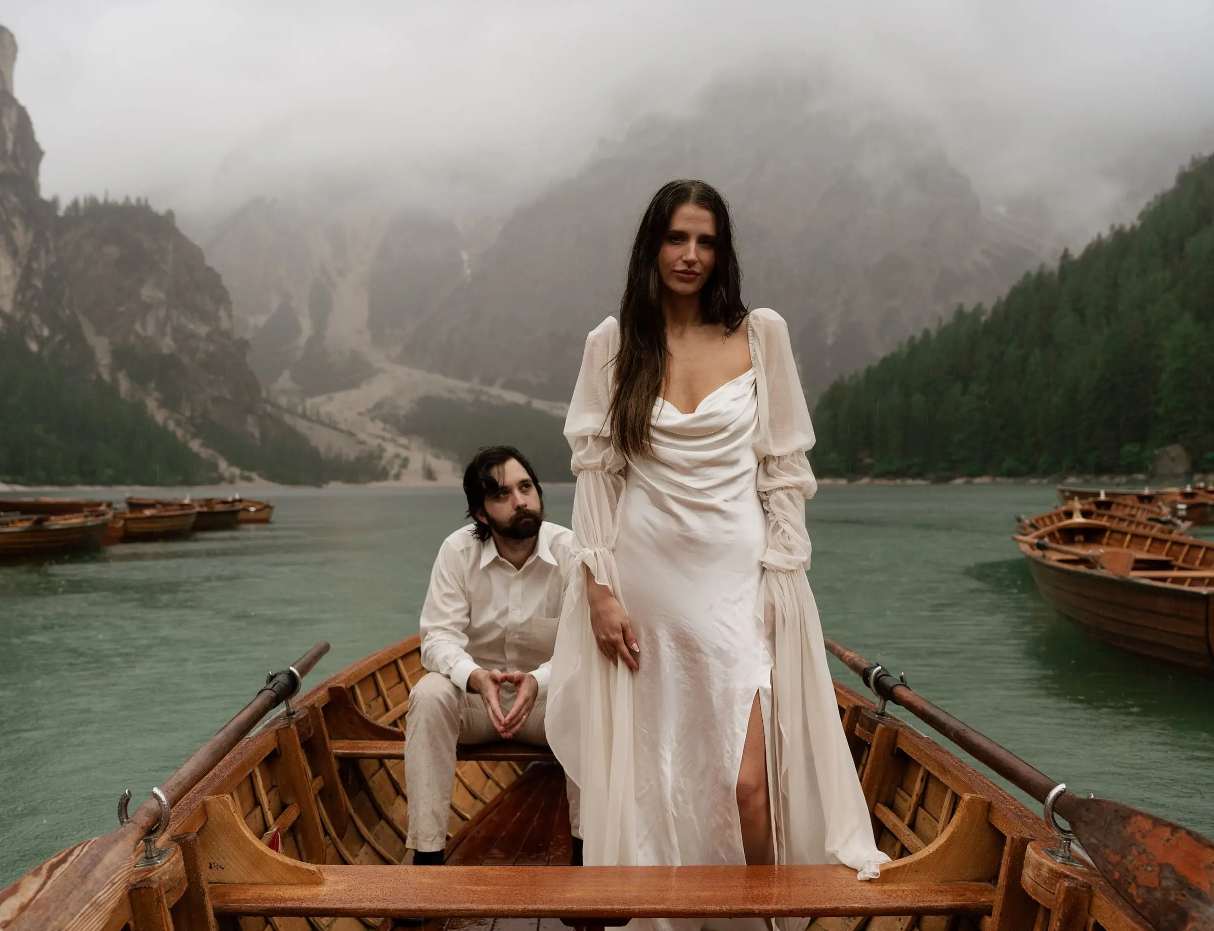 Bride standing in the rowing boat, the groom seated, cliffs in the mist
