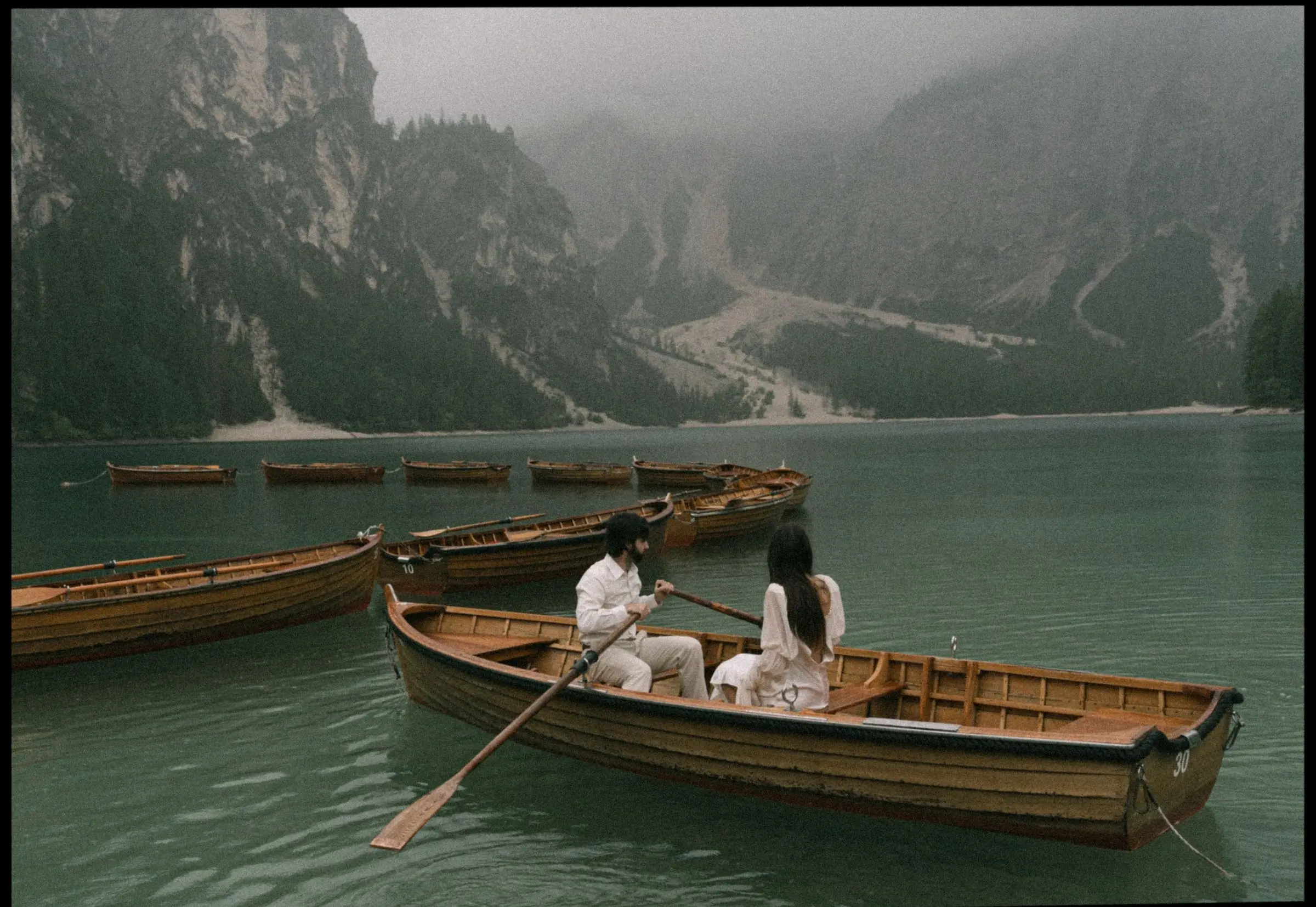 Couple rowing across Lago di Braies on a misty morning, on film