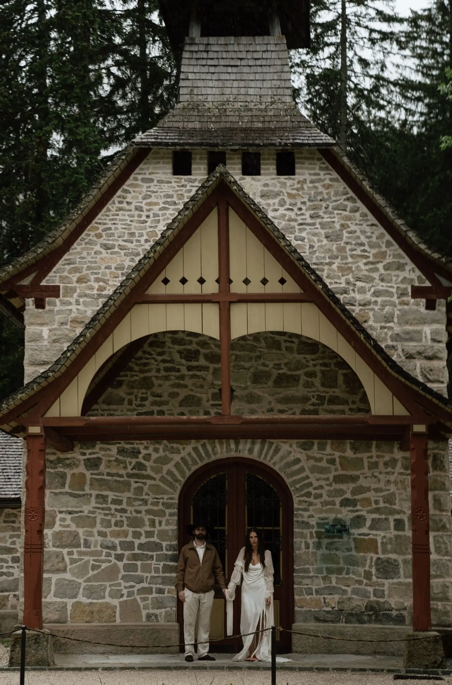 Couple at the door of the stone chapel by Lago di Braies