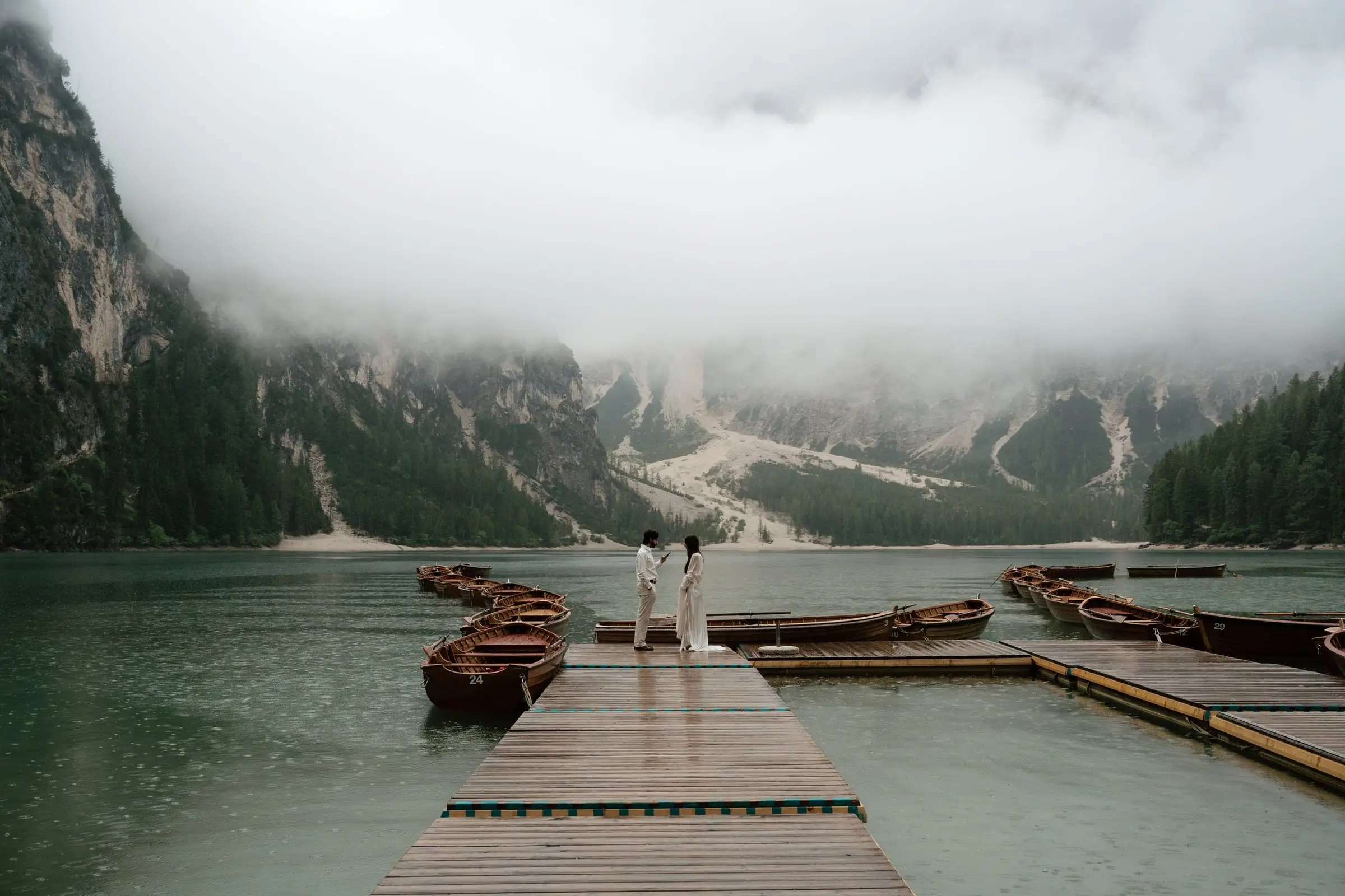 Couple on the long wooden jetty under low clouds at Lago di Braies