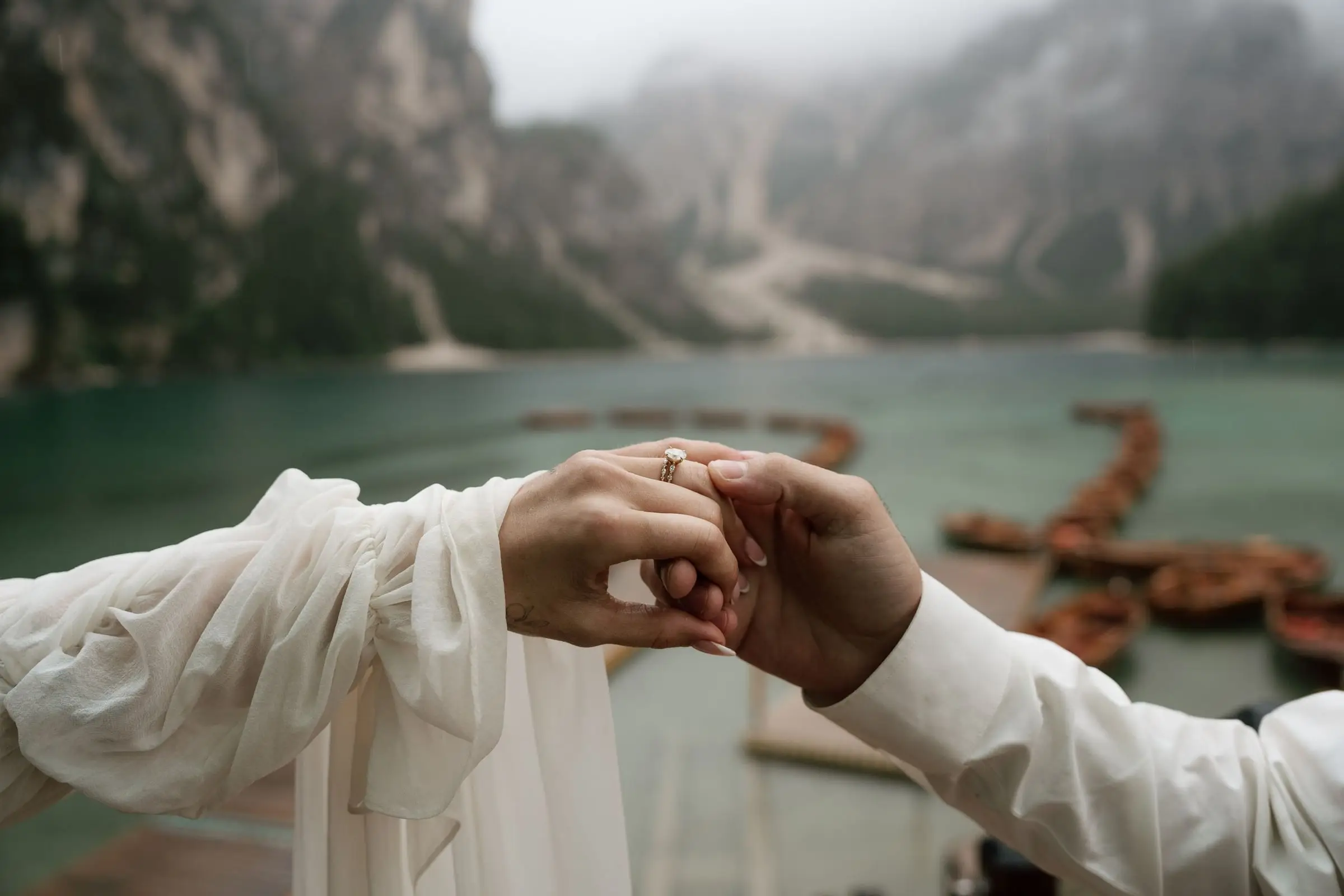 Close-up of joined hands with rings over the misty lake